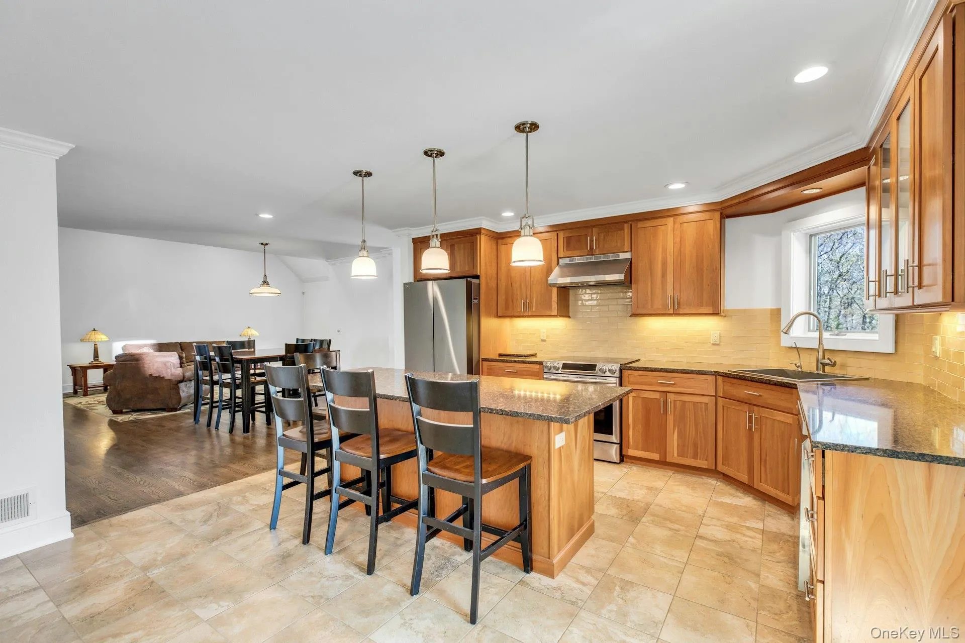 Spacious kitchen featuring warm wood cabinetry, granite countertops, stainless steel appliances, and tile flooring Spacious kitchen featuring warm wood cabinetry, granite countertops, stainless steel appliances, and tile flooring