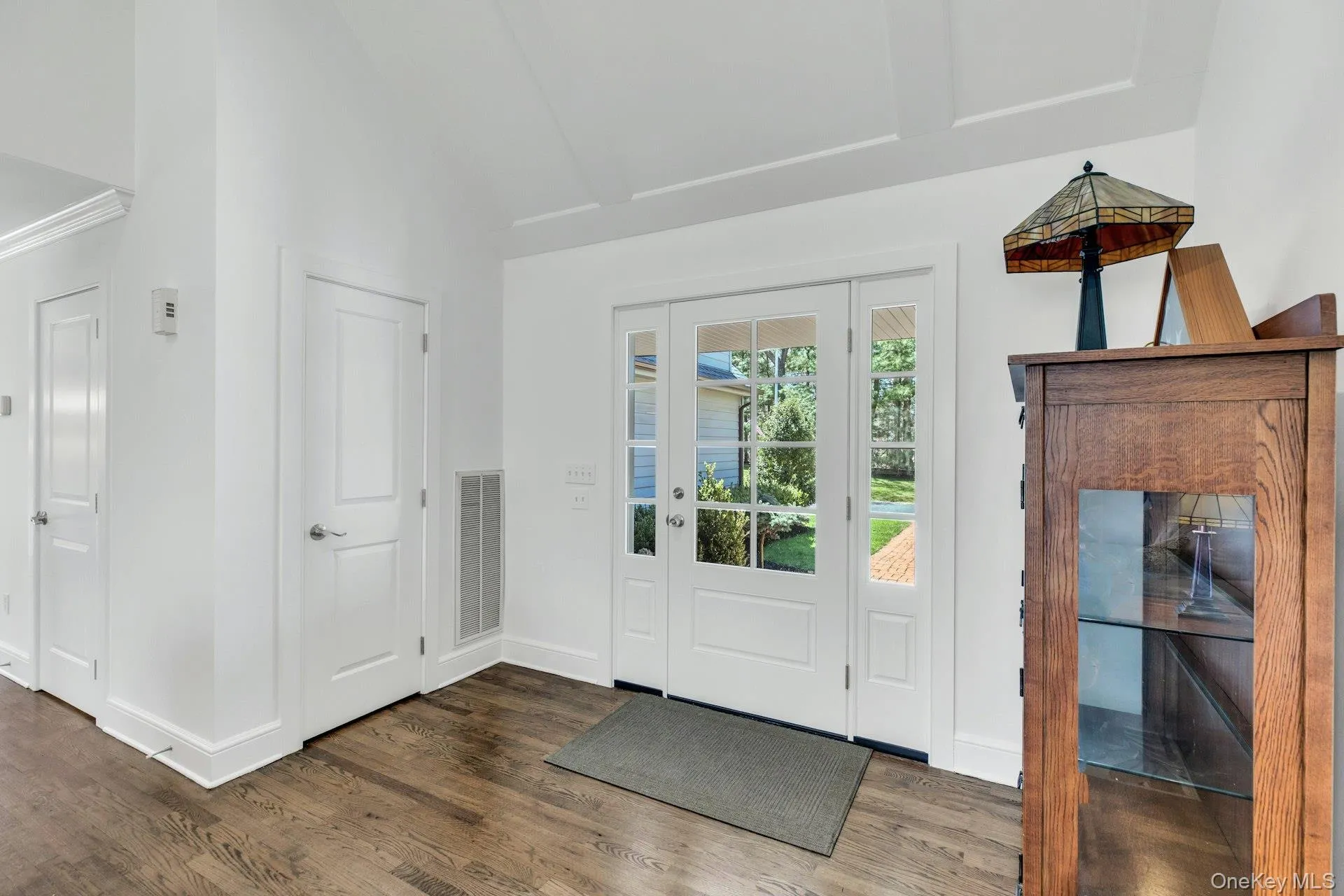 Entryway featuring a glass-paned door with side light, wood-finish flooring, white trim, and a high ceiling with a tray detail Entryway featuring a glass-paned door with side light, wood-finish flooring, white trim, and a high ceiling with a tray detail
