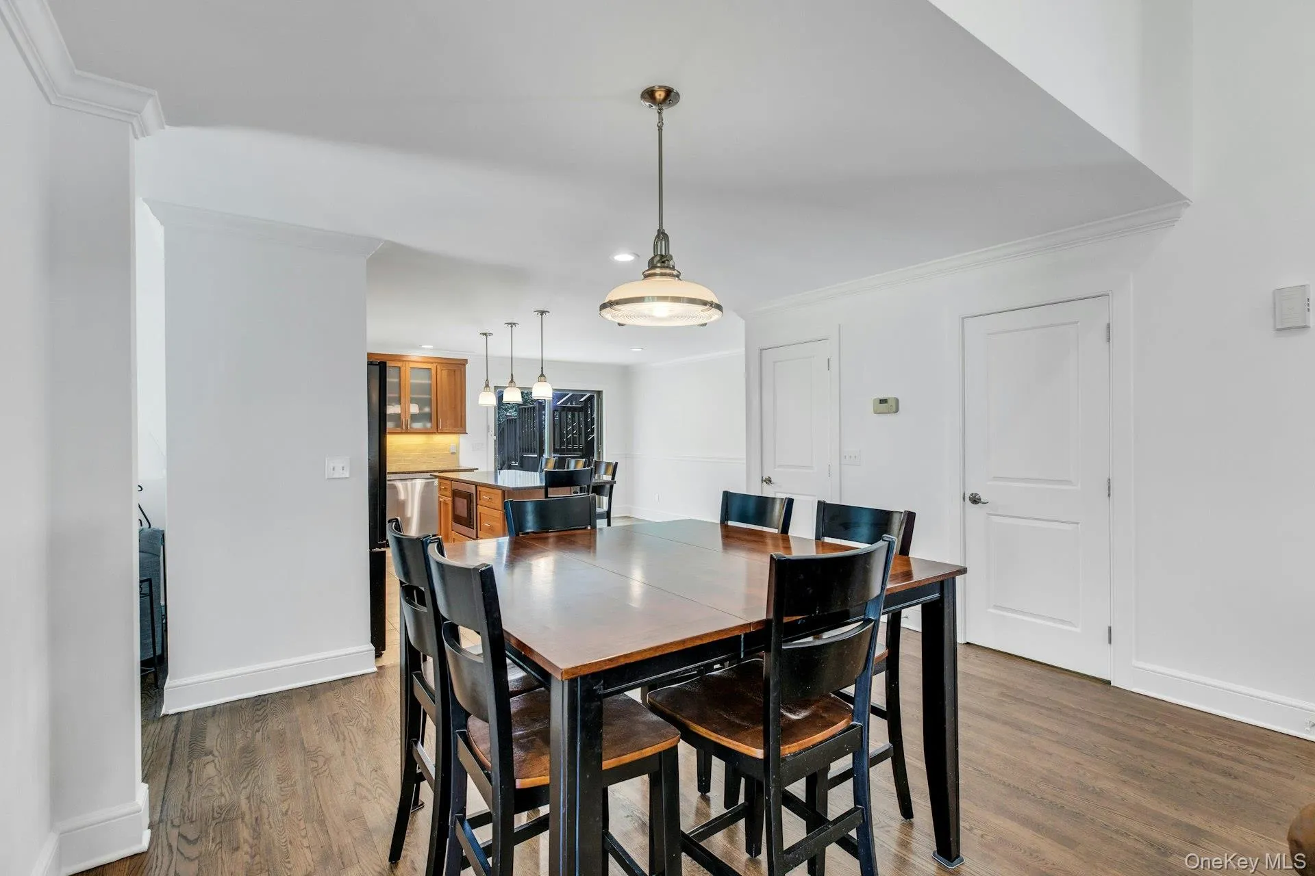 Dining area featuring wood-finish flooring and a central pendant light fixture Dining area featuring wood-finish flooring and a central pendant light fixture