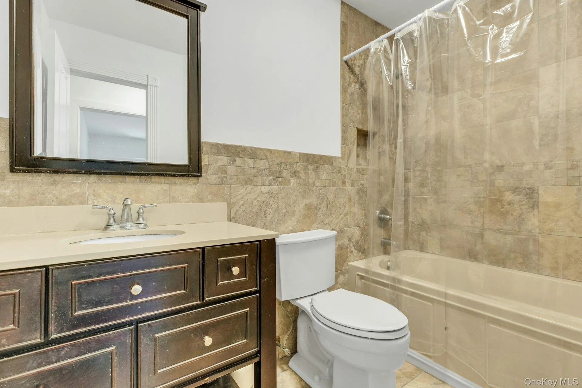 Bathroom featuring a dark wood-finish vanity with a light-toned countertop, an undermount sink, and a framed mirror Bathroom featuring a dark wood-finish vanity with a light-toned countertop, an undermount sink, and a framed mirror