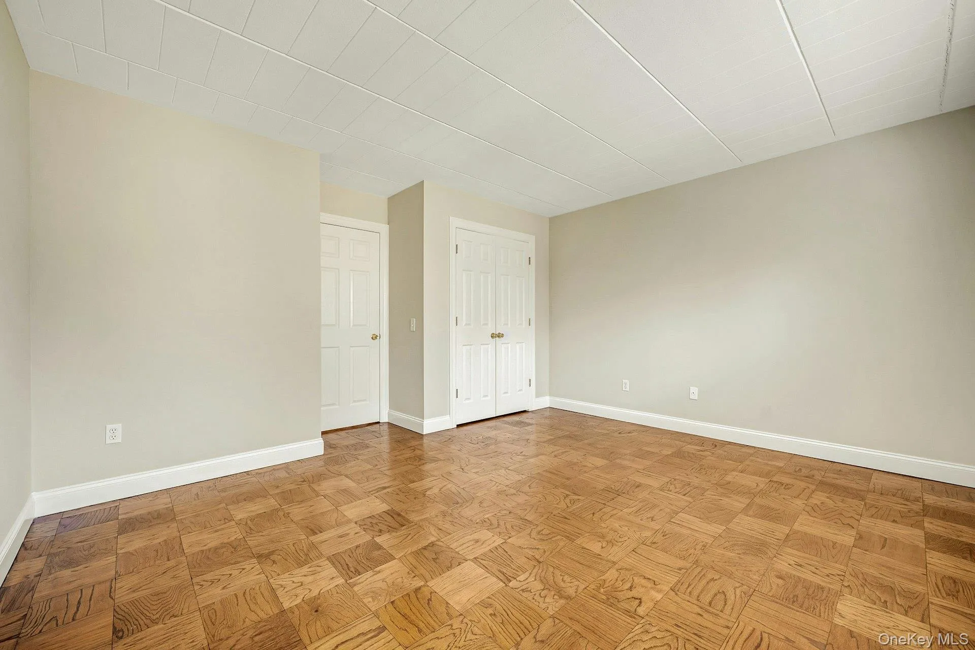 This room features parquet flooring, light-colored walls, and white trim This room features parquet flooring, light-colored walls, and white trim
