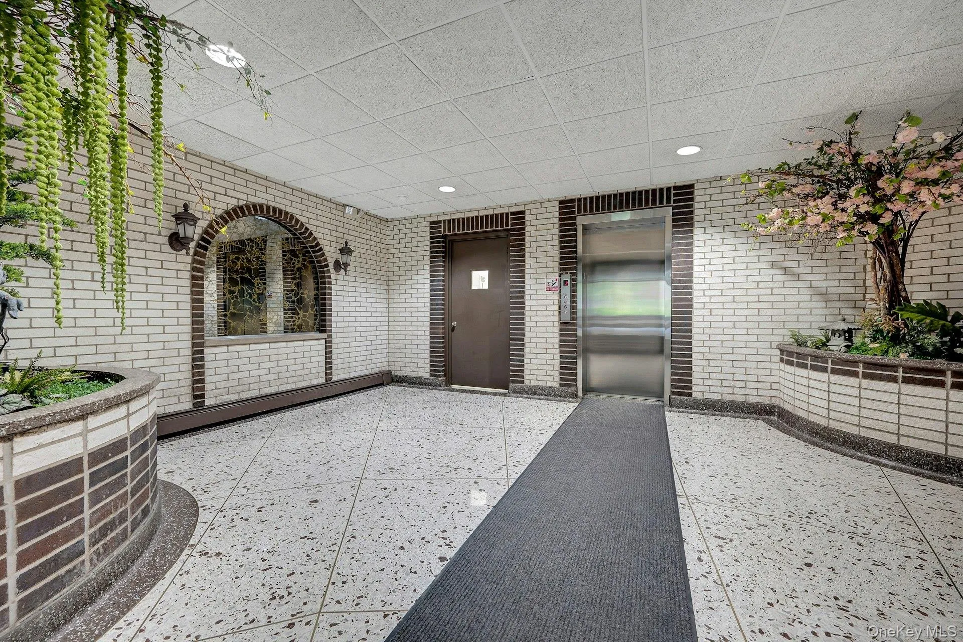 The property features a well-maintained lobby with white brick walls, terrazzo flooring, and recessed lighting The property features a well-maintained lobby with white brick walls, terrazzo flooring, and recessed lighting