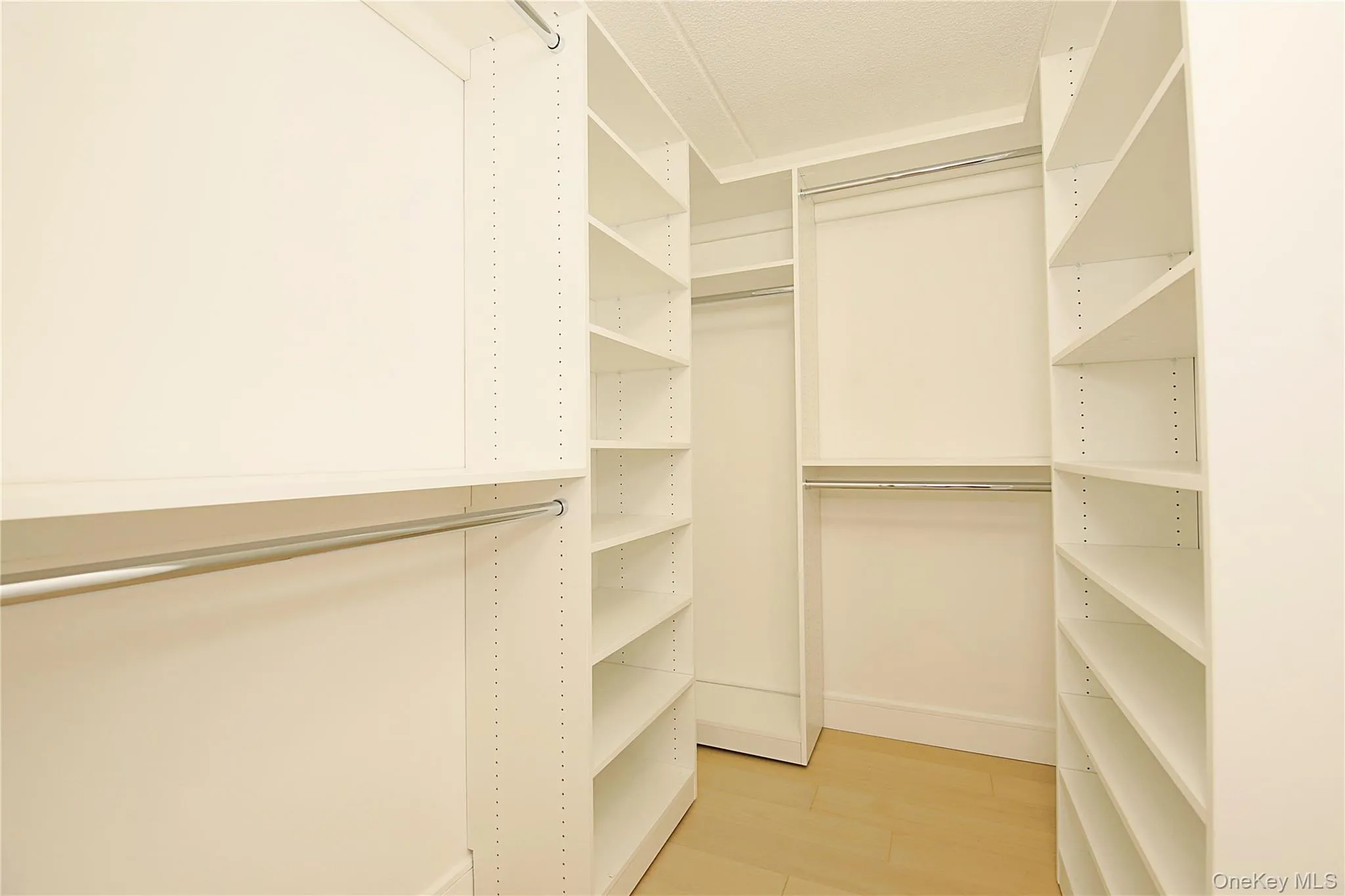 This walk-in closet features extensive built-in shelving, hanging rods, and light-toned flooring This walk-in closet features extensive built-in shelving, hanging rods, and light-toned flooring