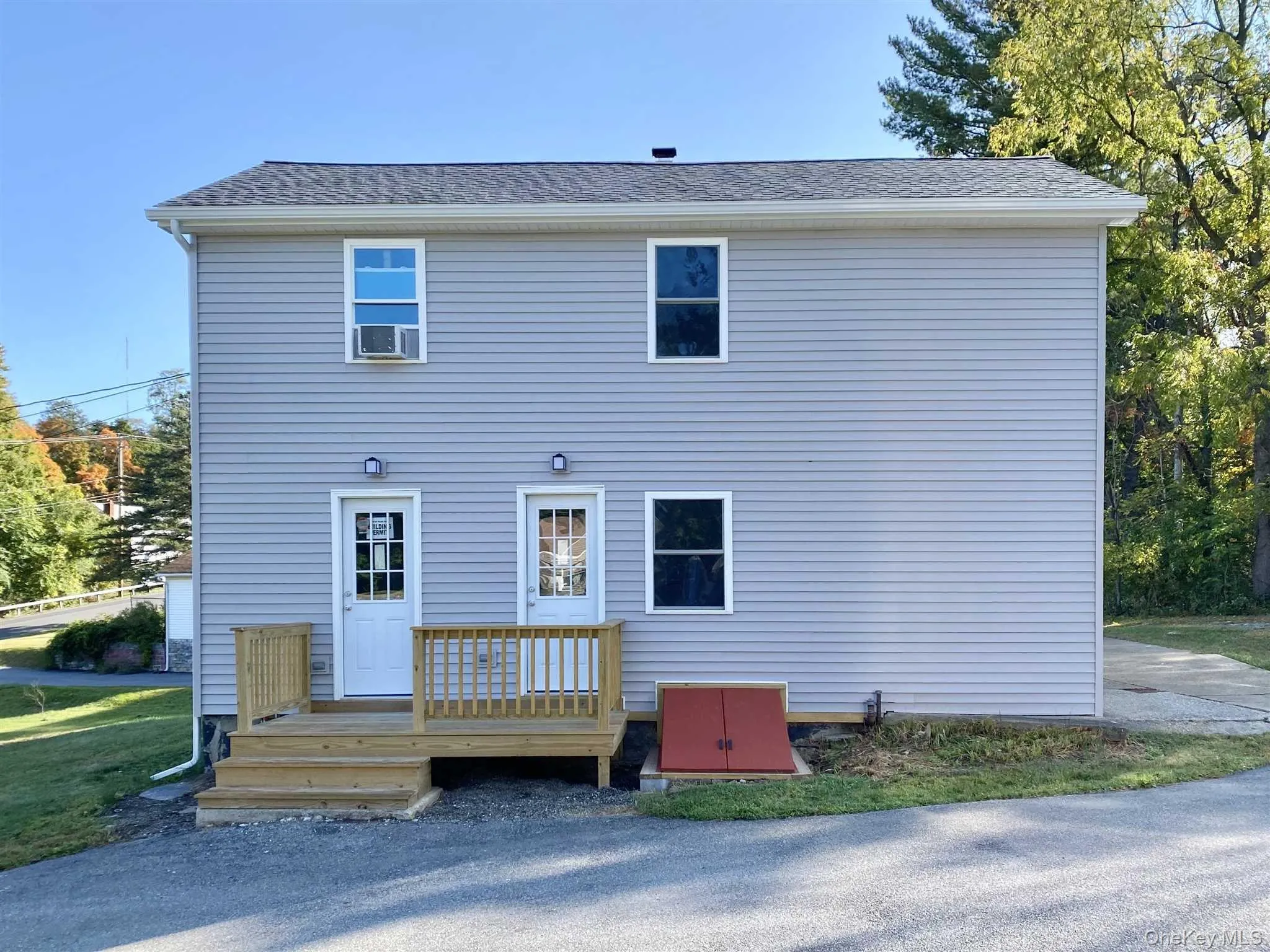 The property features light gray horizontal siding, a gray shingled roof, and white window trim The property features light gray horizontal siding, a gray shingled roof, and white window trim