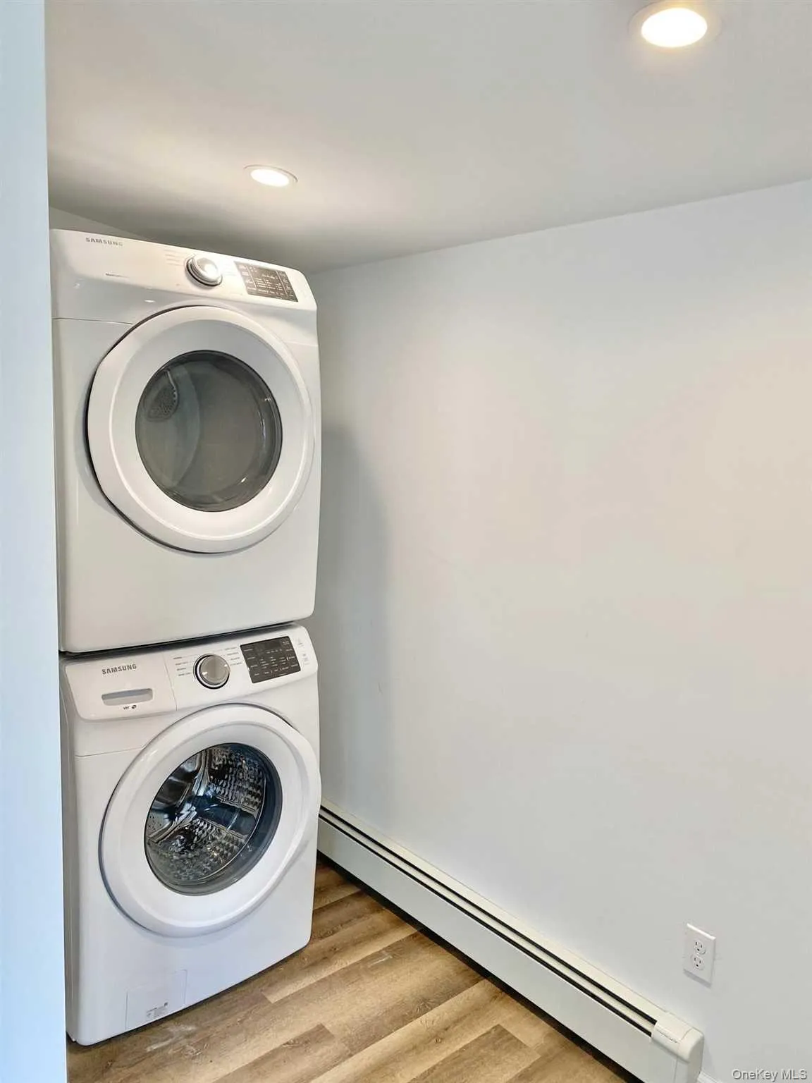 This property features a laundry area with a stacked washer and dryer, recessed ceiling lighting, and wood-look flooring This property features a laundry area with a stacked washer and dryer, recessed ceiling lighting, and wood-look flooring