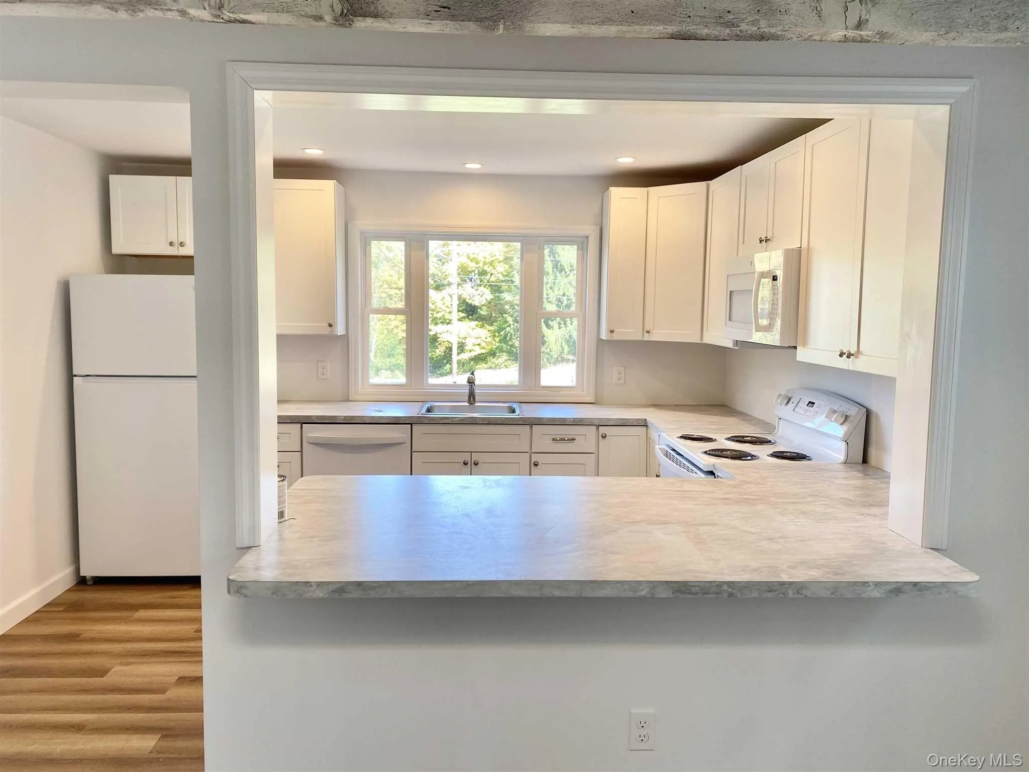 The kitchen features white cabinetry, white appliances, and light-colored countertops The kitchen features white cabinetry, white appliances, and light-colored countertops