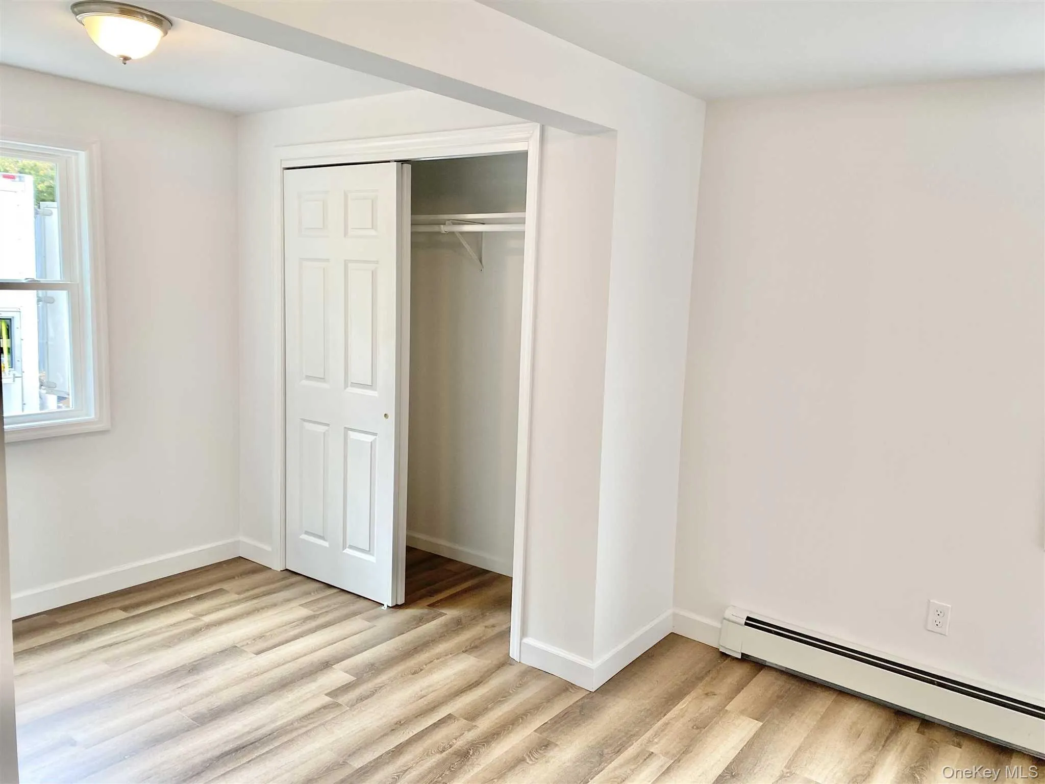 This room features light-colored walls, light wood-style flooring, and a window providing natural light This room features light-colored walls, light wood-style flooring, and a window providing natural light