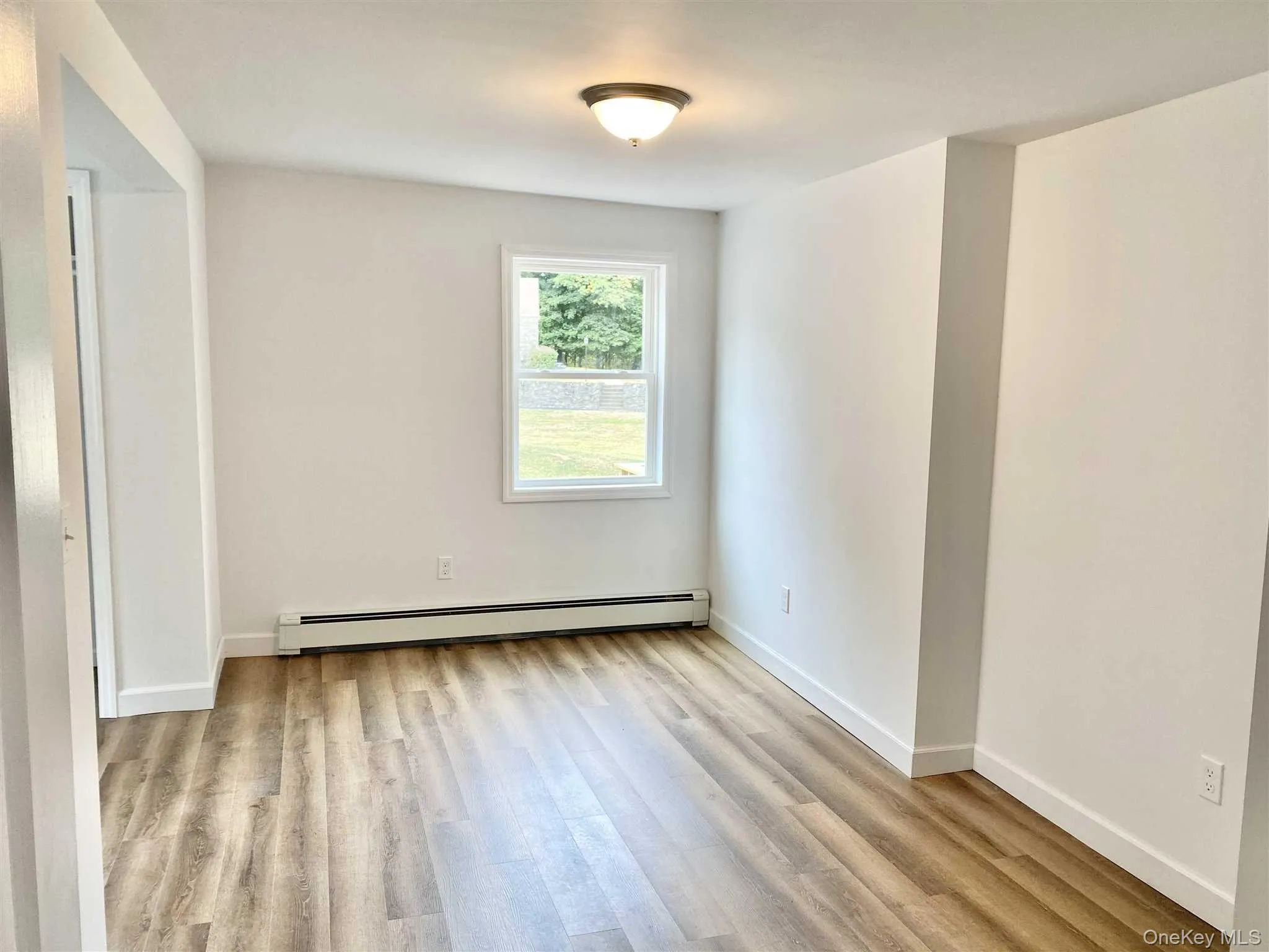 This room features neutral walls, a window providing natural light and exterior views, and wood-style flooring This room features neutral walls, a window providing natural light and exterior views, and wood-style flooring