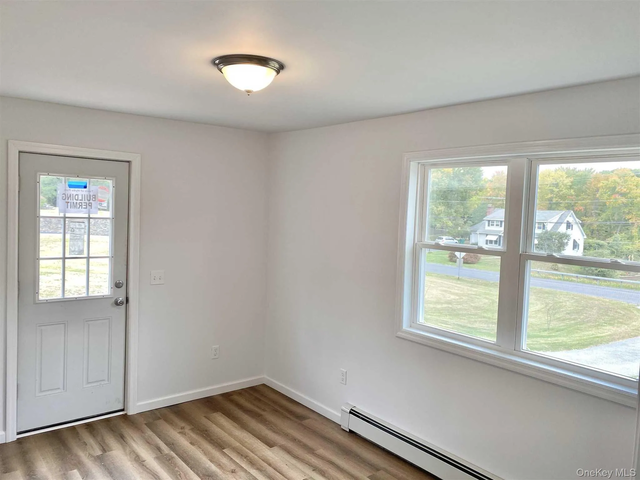This room features light-toned walls, wood-style flooring, and a window with a view of the surrounding landscape. Exterior access This room features light-toned walls, wood-style flooring, and a window with a view of the surrounding landscape. Exterior access