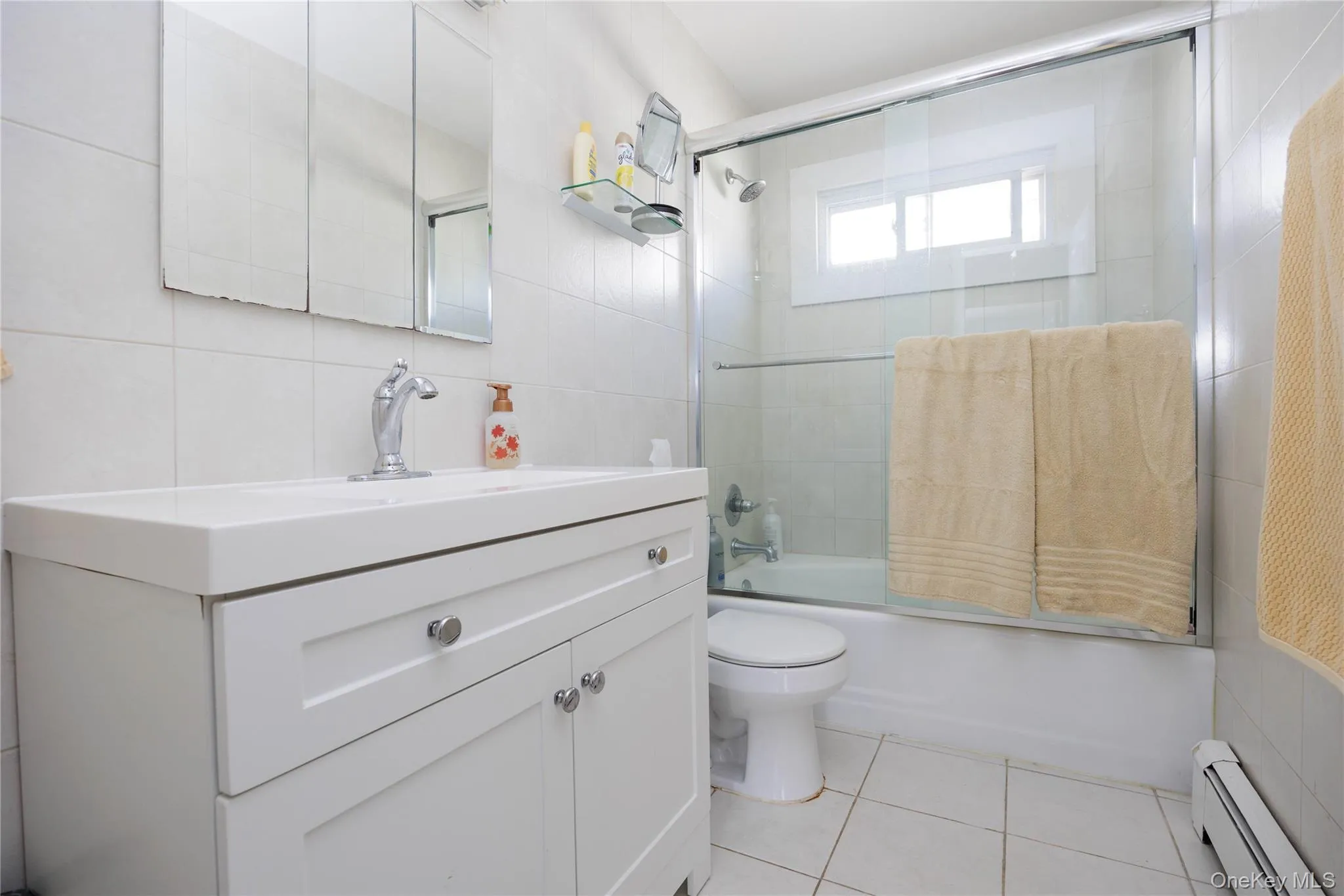 Bathroom featuring a baseboard radiator, tile walls, toilet, tile patterned floors, and vanity Bathroom featuring a baseboard radiator, tile walls, toilet, tile patterned floors, and vanity