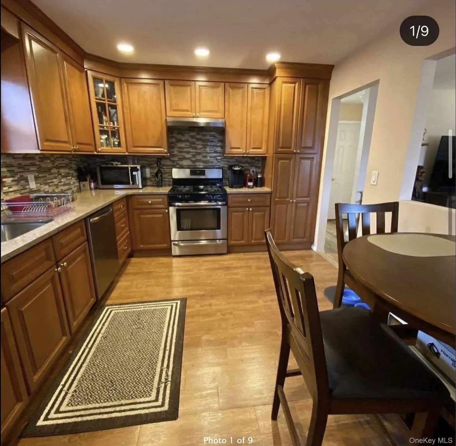 Kitchen featuring appliances with stainless steel finishes, brown cabinets, light wood-type flooring, decorative backsplash, and recessed lighting Kitchen featuring appliances with stainless steel finishes, brown cabinets, light wood-type flooring, decorative backsplash, and recessed lighting