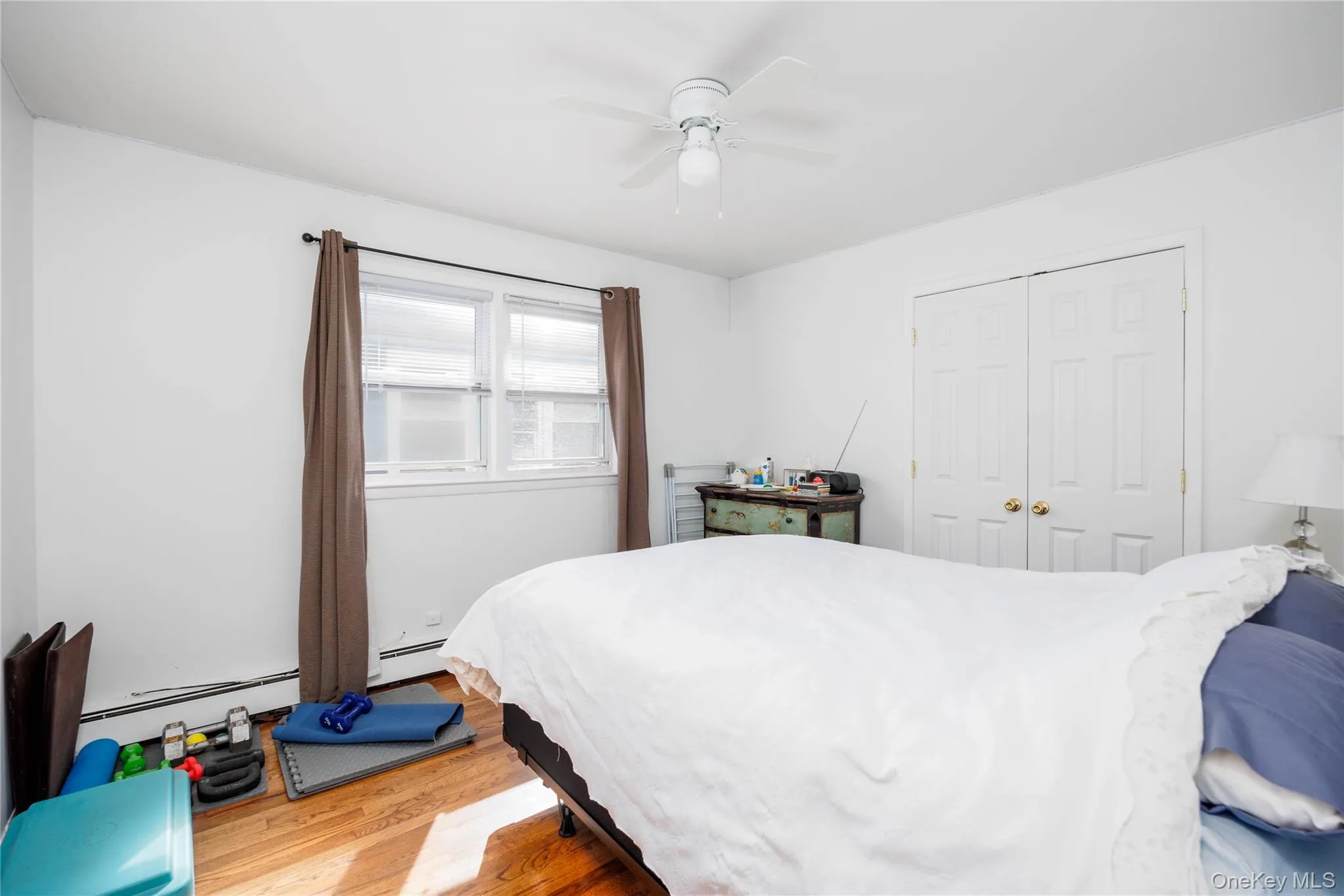 Bedroom with wood finished floors, a closet, ceiling fan, and a baseboard radiator Bedroom with wood finished floors, a closet, ceiling fan, and a baseboard radiator