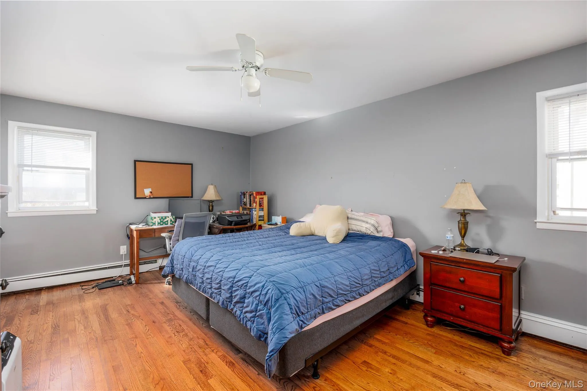 Bedroom with baseboard heating, wood finished floors, ceiling fan, and baseboards Bedroom with baseboard heating, wood finished floors, ceiling fan, and baseboards
