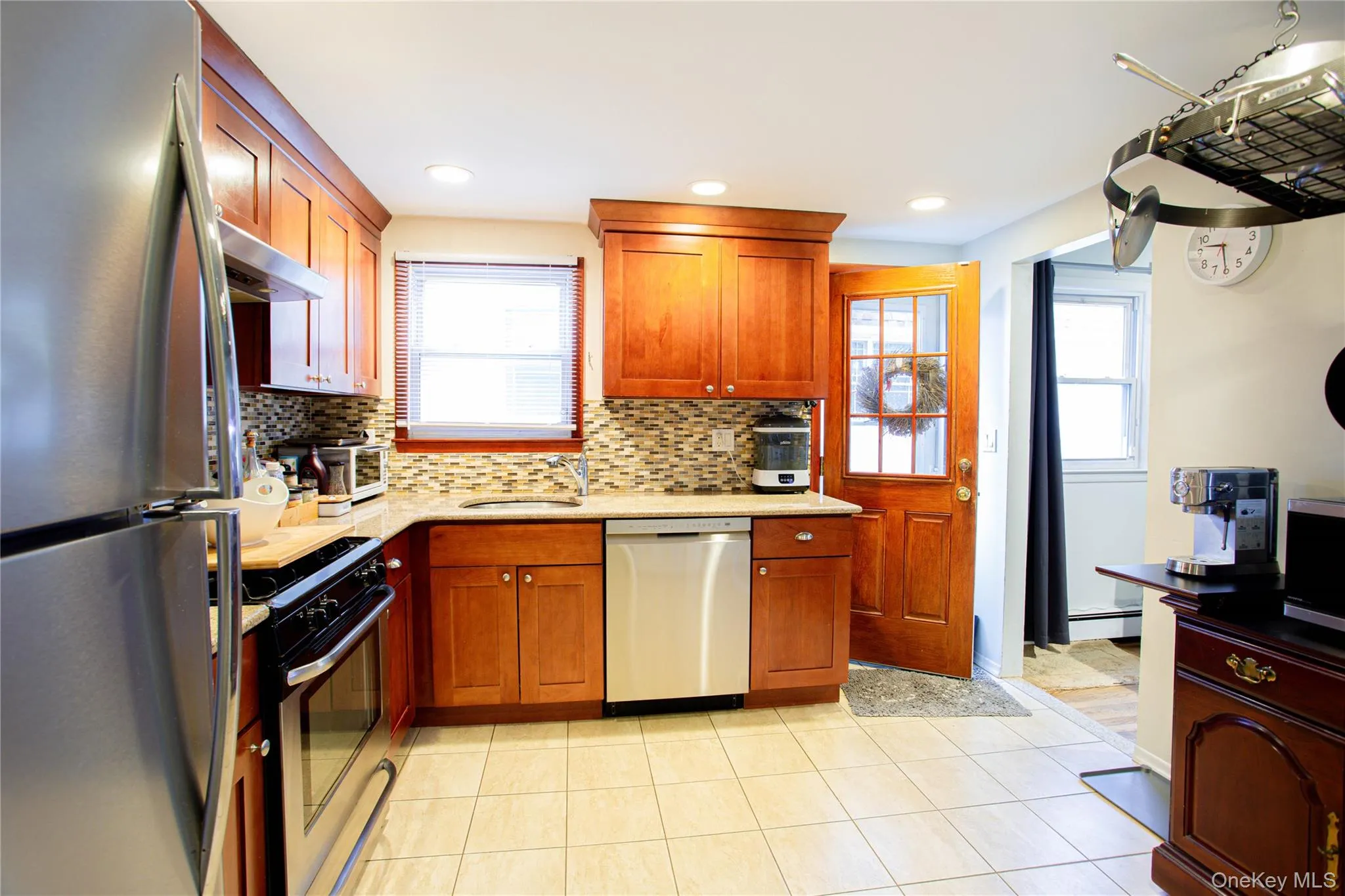 Kitchen featuring under cabinet range hood, a wealth of natural light, a sink, and stainless steel appliances Kitchen featuring under cabinet range hood, a wealth of natural light, a sink, and stainless steel appliances