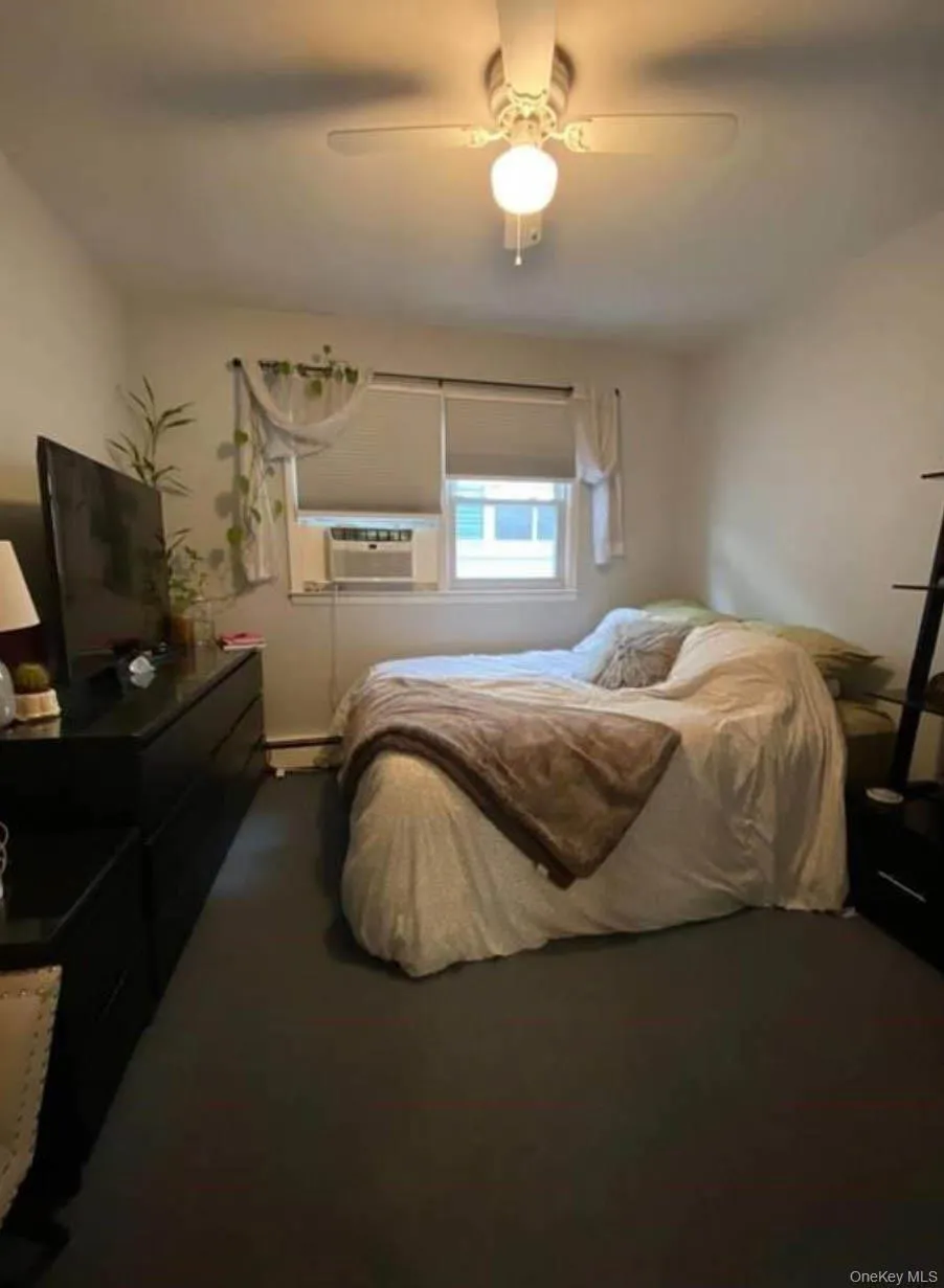 Carpeted bedroom with a ceiling fan and cooling unit Carpeted bedroom with a ceiling fan and cooling unit