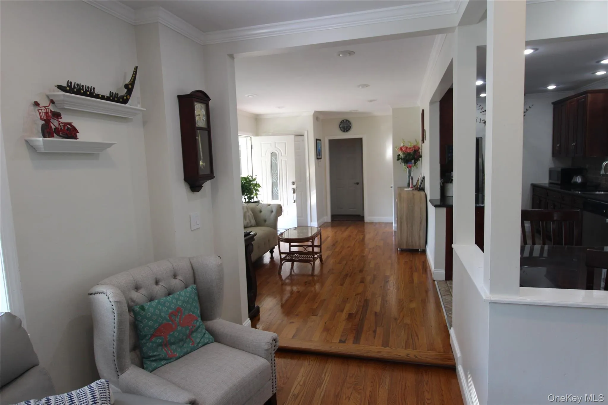 Wood flooring extending through multiple areas, crown molding, recessed lighting, white trim, and a white paneled entry door. Wood flooring extending through multiple areas, crown molding, recessed lighting, white trim, and a white paneled entry door.