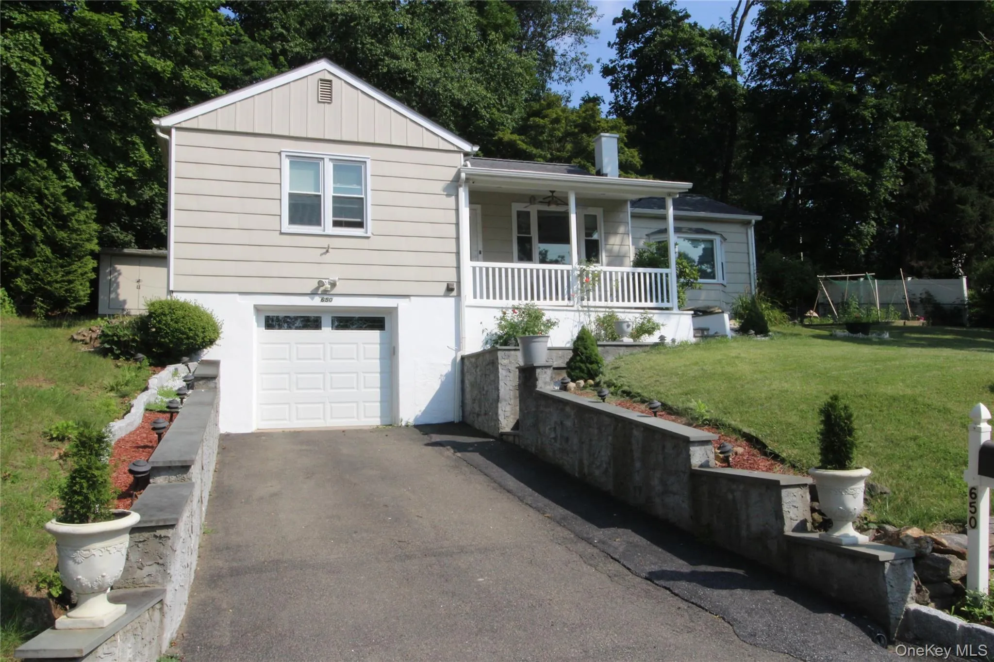 650 Warren Avenue is featuring a single-car garage, a covered front porch with white railings, and a tiered retaining wall bordering the driveway. 650 Warren Avenue is featuring a single-car garage, a covered front porch with white railings, and a tiered retaining wall bordering the driveway.