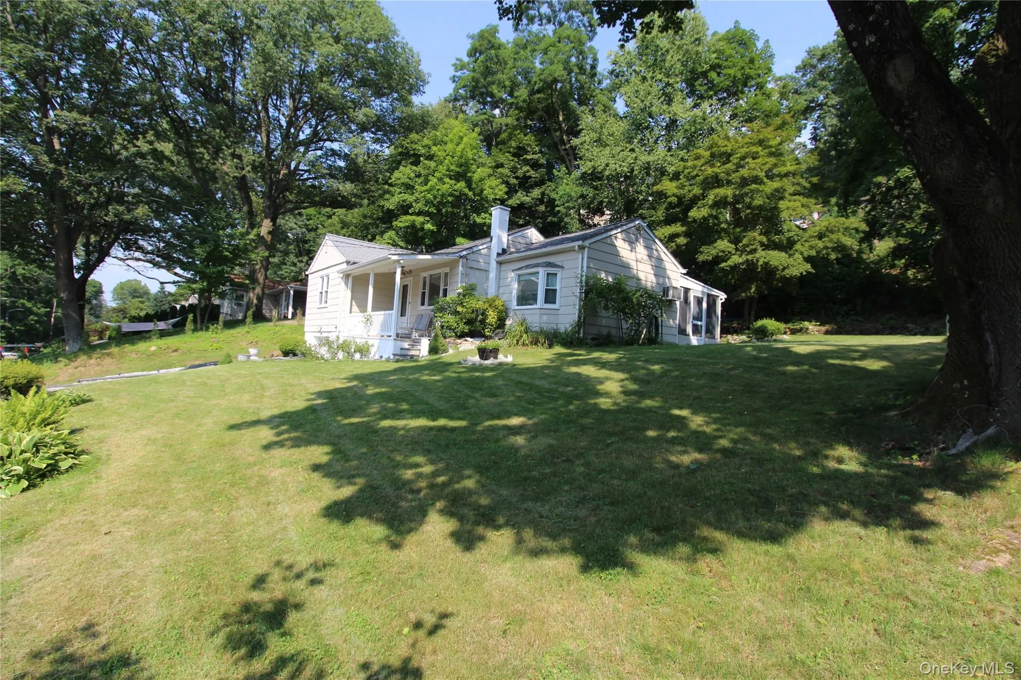 White siding residence featuring a covered porch, front and side yard has plenty of room to garden, mature perimeter trees, and a tree-shaded lawn. White siding residence featuring a covered porch, front and side yard has plenty of room to garden, mature perimeter trees, and a tree-shaded lawn.
