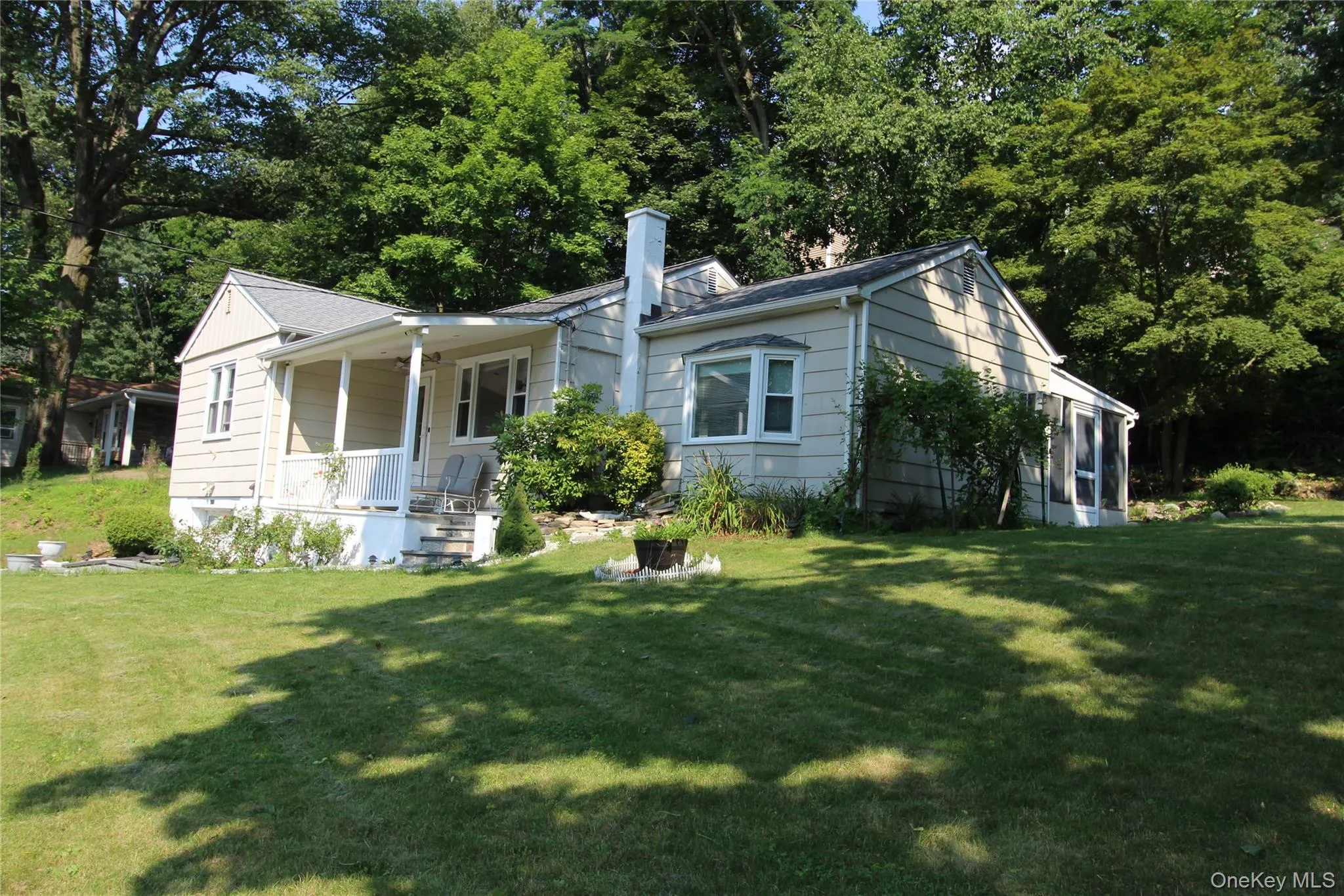 Cream-colored siding exterior with a covered front porch featuring white railings Cream-colored siding exterior with a covered front porch featuring white railings