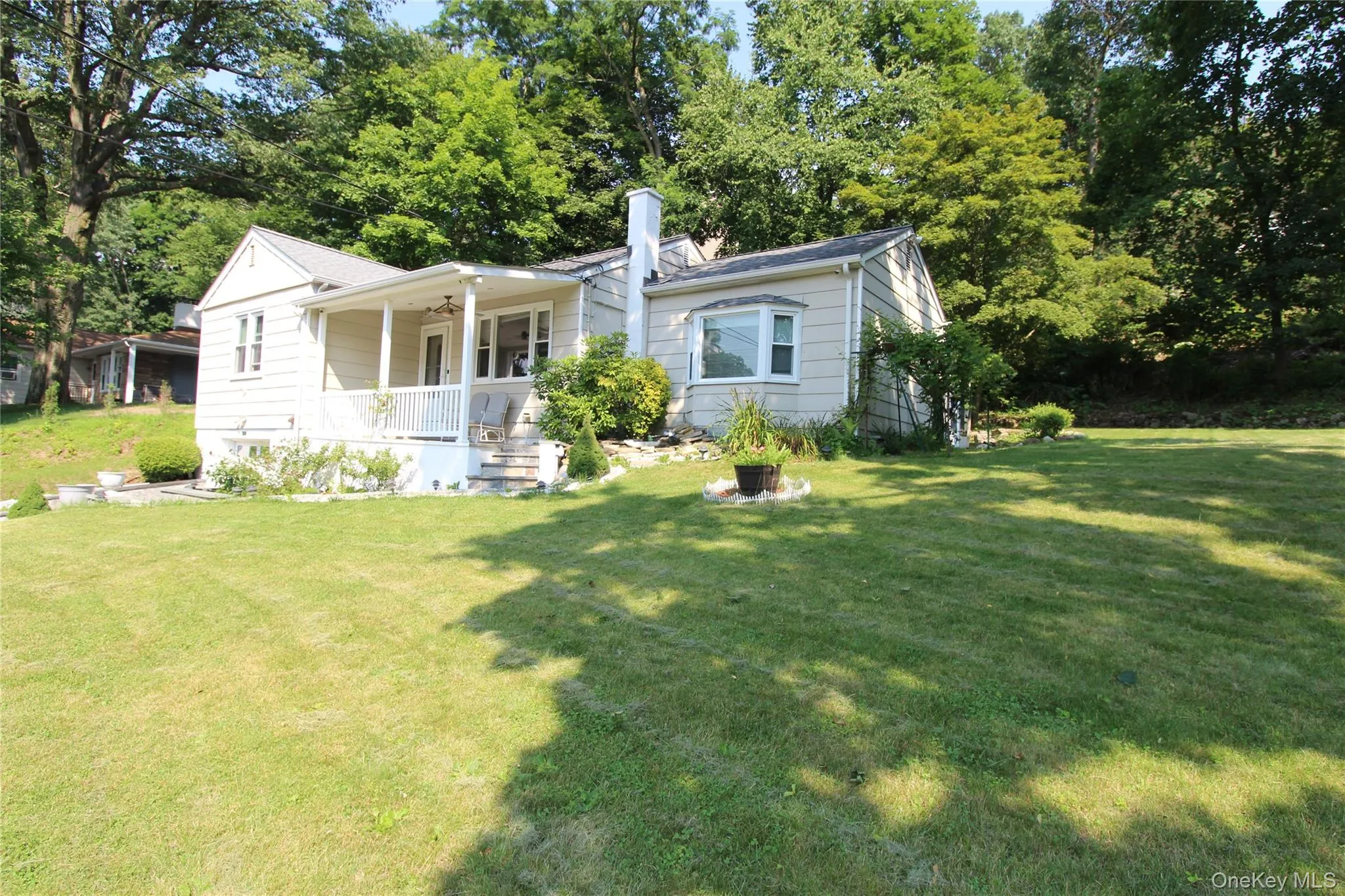 Spacious front lawn with mature trees and a traditional light-colored siding home Spacious front lawn with mature trees and a traditional light-colored siding home