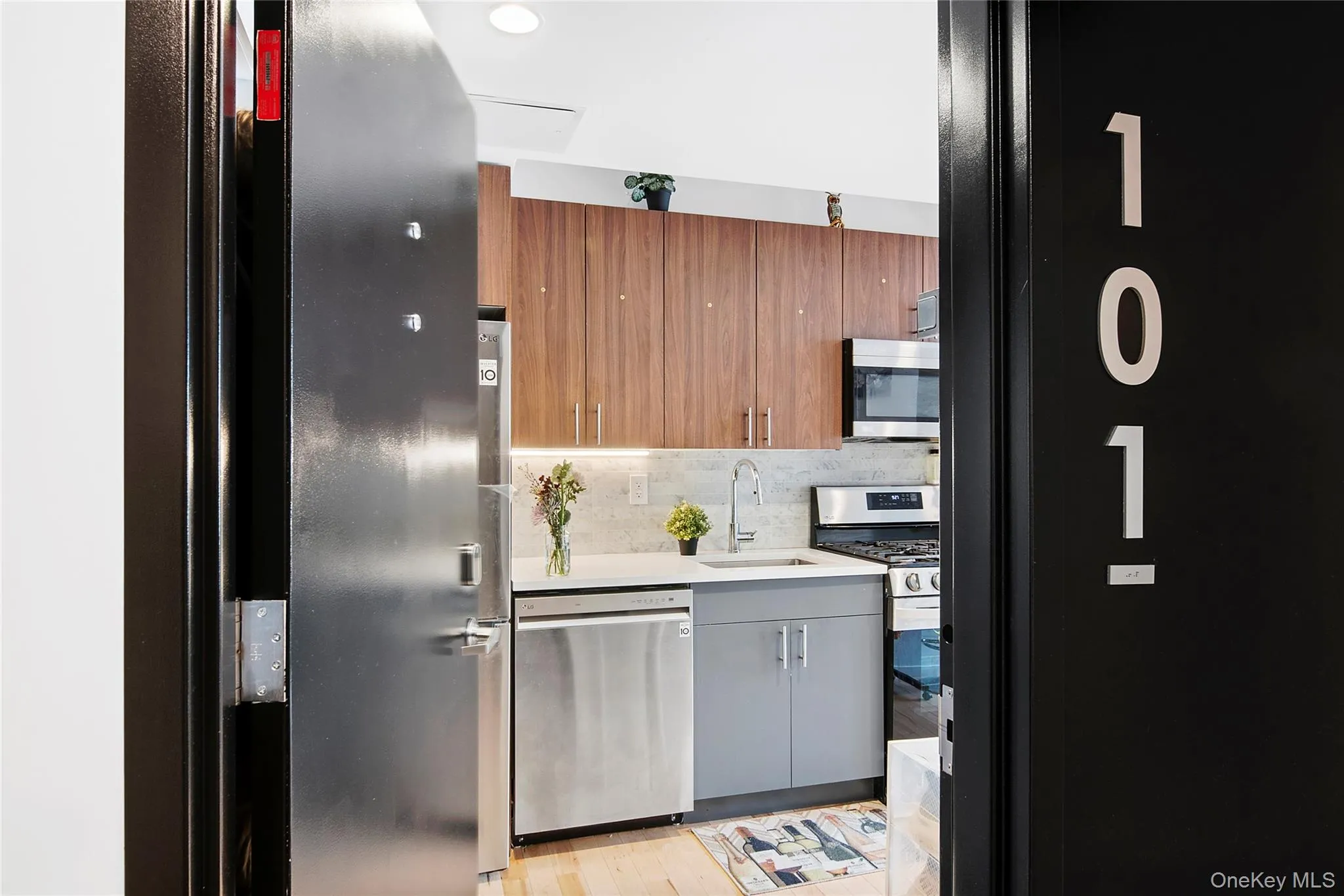 Compact kitchen featuring modern wood-finish cabinetry, light-toned countertop, stainless steel appliances, and a gas range Compact kitchen featuring modern wood-finish cabinetry, light-toned countertop, stainless steel appliances, and a gas range