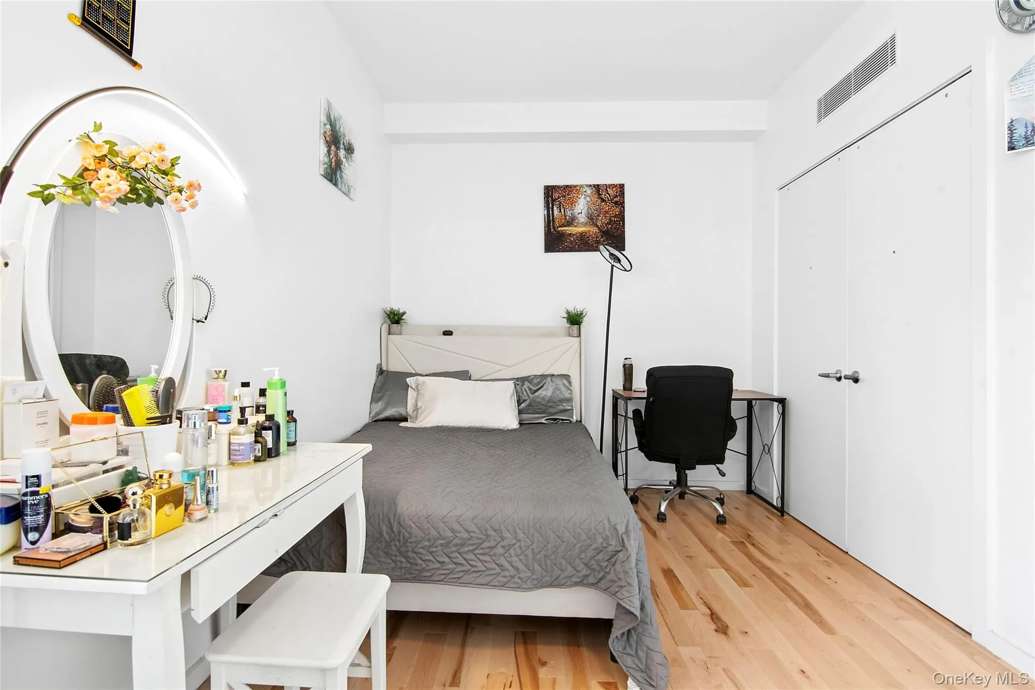 Bedroom featuring wood-finish flooring, a white wardrobe, and a built-in ventilation system Bedroom featuring wood-finish flooring, a white wardrobe, and a built-in ventilation system