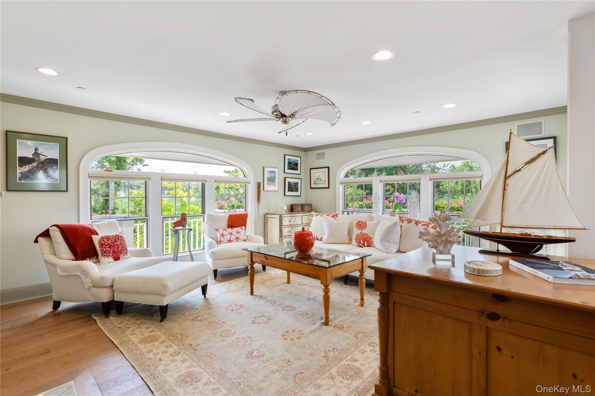 Professional appointed living area featuring ornamental crown and base moulding, recessed lighting, light wood-type flooring, and plenty of natural light. Professional appointed living area featuring ornamental crown and base moulding, recessed lighting, light wood-type flooring, and plenty of natural light.
