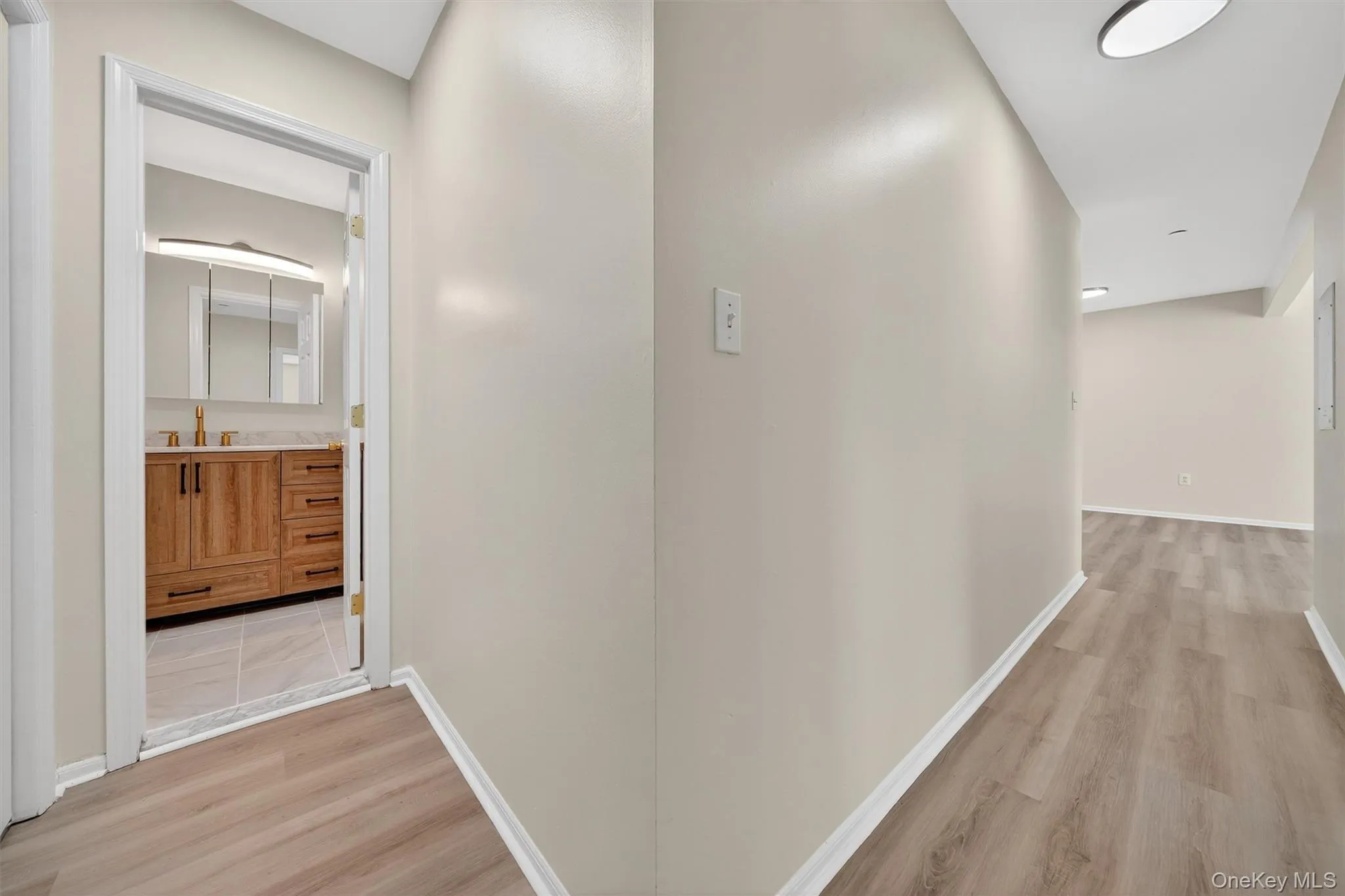 Corridor featuring light wood-type flooring and baseboards Corridor featuring light wood-type flooring and baseboards