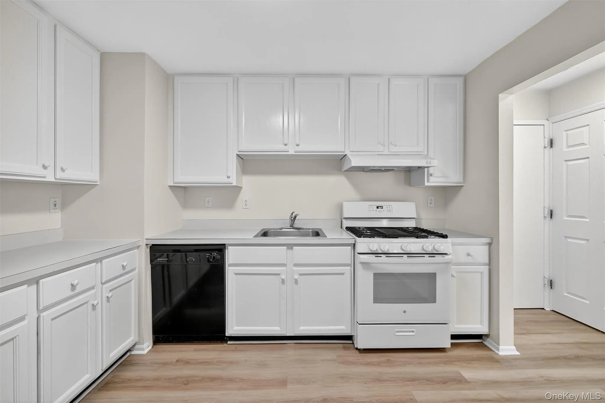 Kitchen with gas range gas stove, white cabinets, dishwasher, and light countertops Kitchen with gas range gas stove, white cabinets, dishwasher, and light countertops