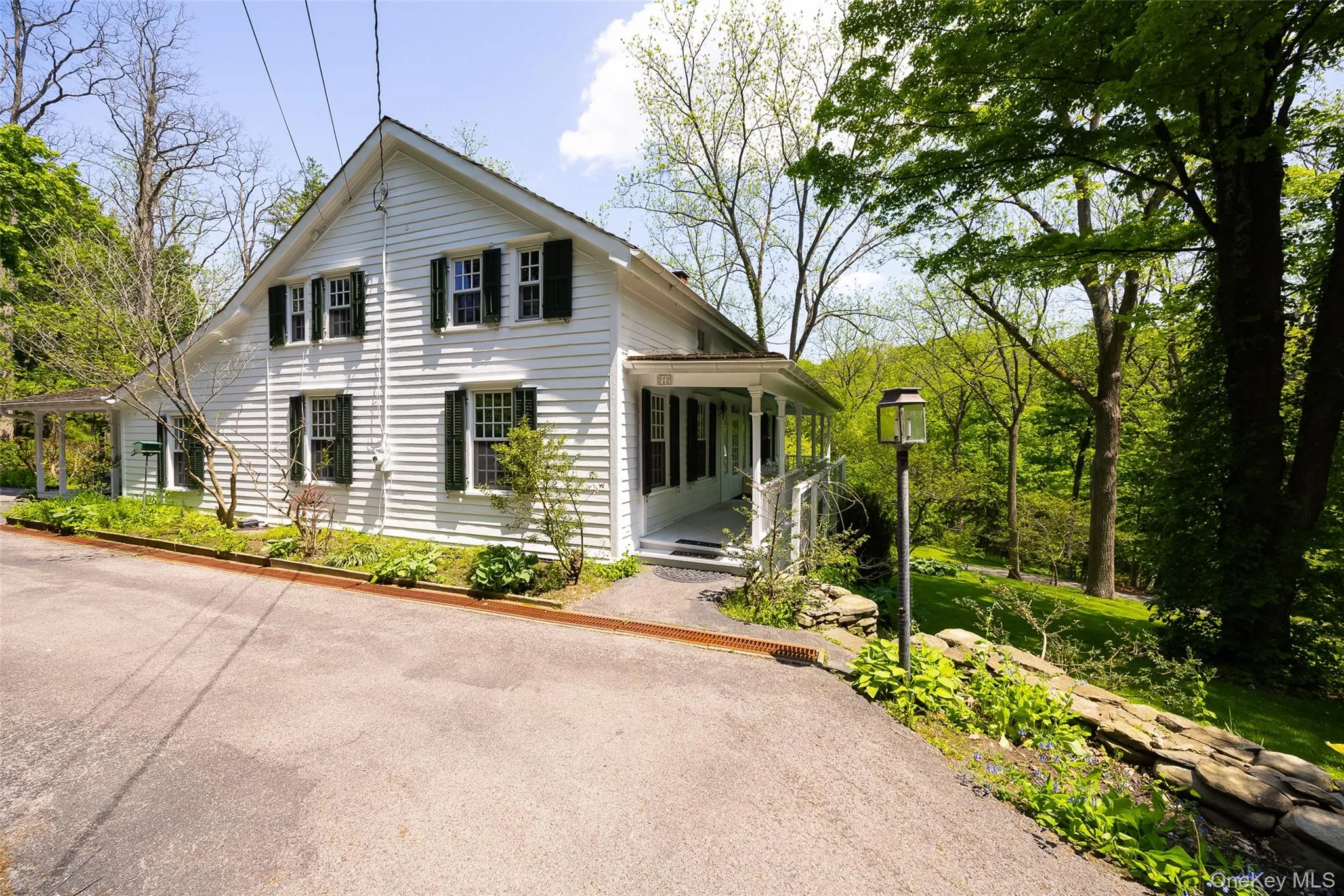 White cedar exterior featuring a covered front porch and a paved driveway White cedar exterior featuring a covered front porch and a paved driveway