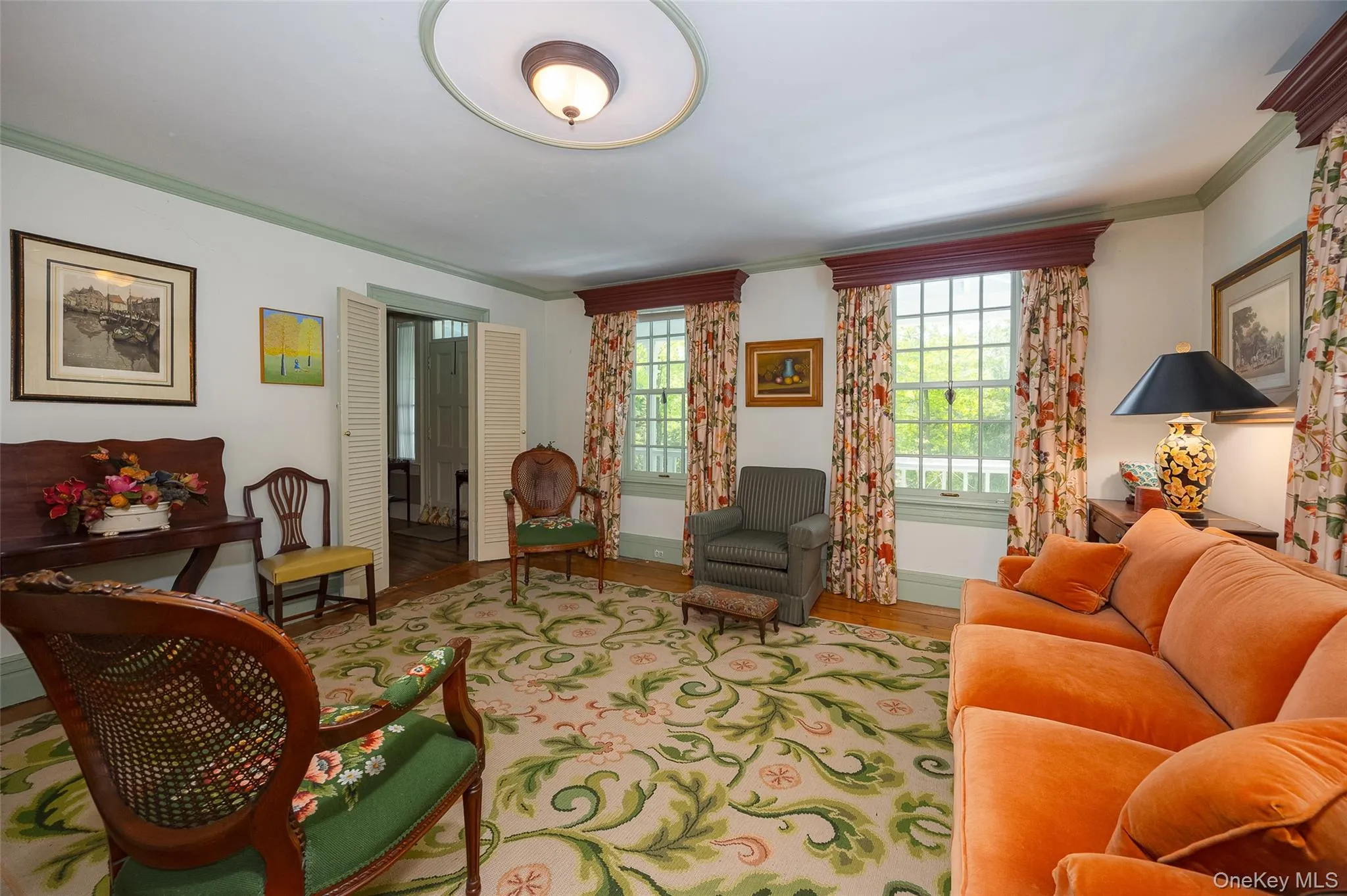 Spacious room featuring hardwood flooring, extensive crown molding, and a central ceiling light fixture Spacious room featuring hardwood flooring, extensive crown molding, and a central ceiling light fixture