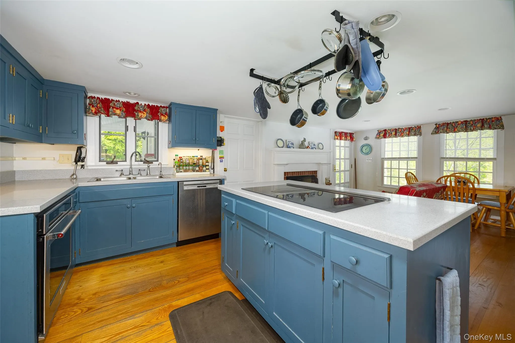 Kitchen featuring a center island with GE Monogram 5-burner induction cooktop, stainless steel appliances, and wood flooring Kitchen featuring a center island with GE Monogram 5-burner induction cooktop, stainless steel appliances, and wood flooring