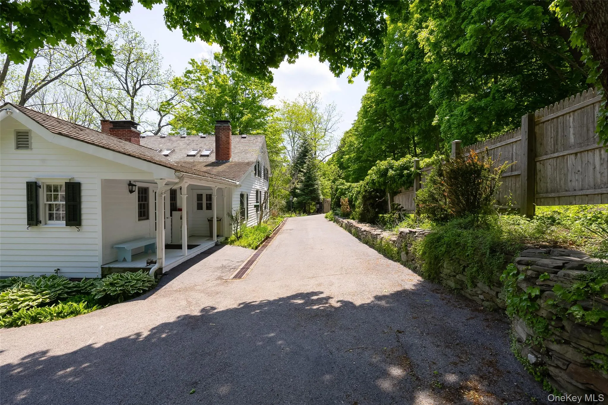 Long paved driveway bordering a hydrangea draped fence Long paved driveway bordering a hydrangea draped fence