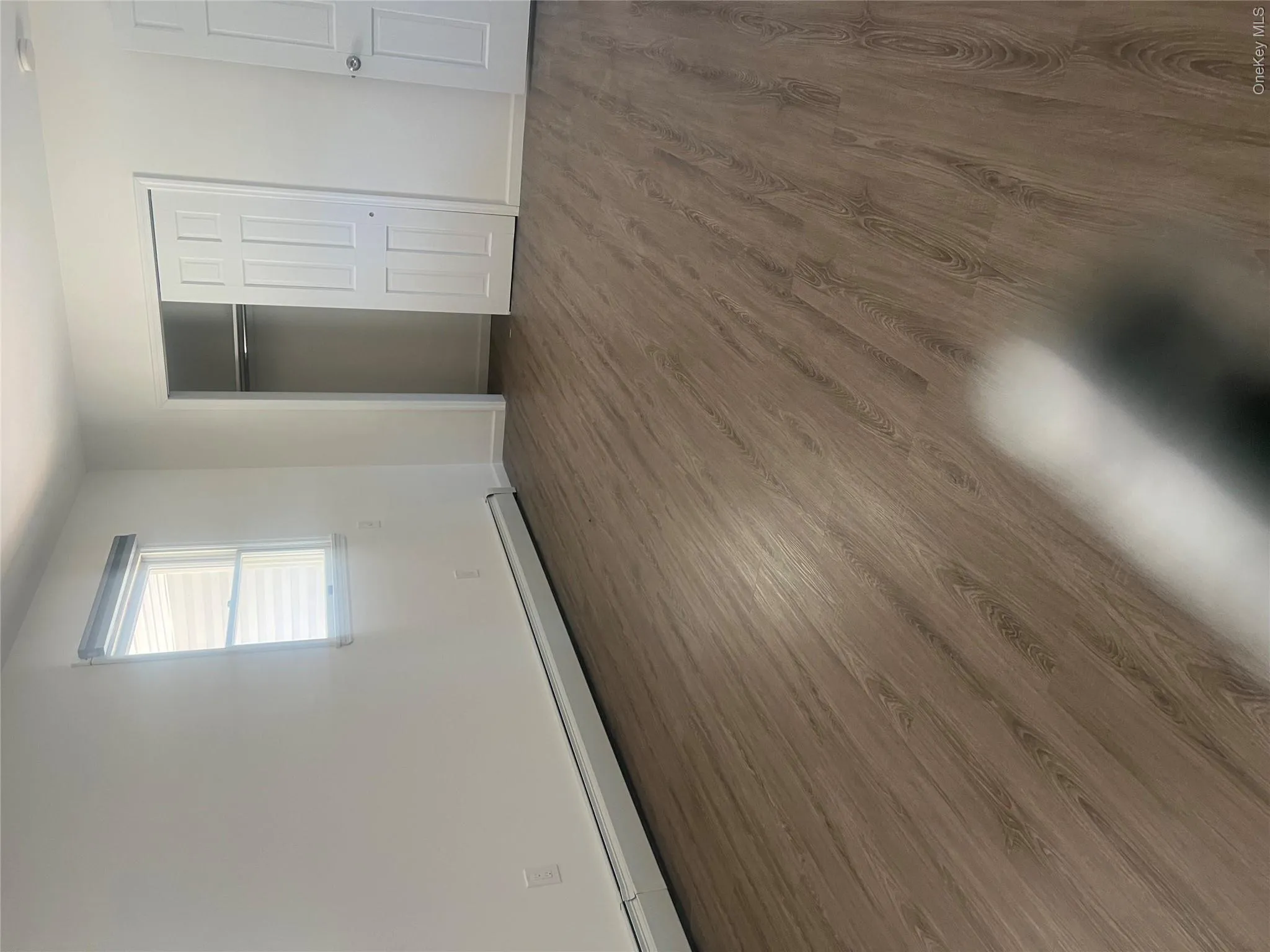 Room featuring wood-style flooring, a window with blinds, and a built-in closet with sliding doors Room featuring wood-style flooring, a window with blinds, and a built-in closet with sliding doors