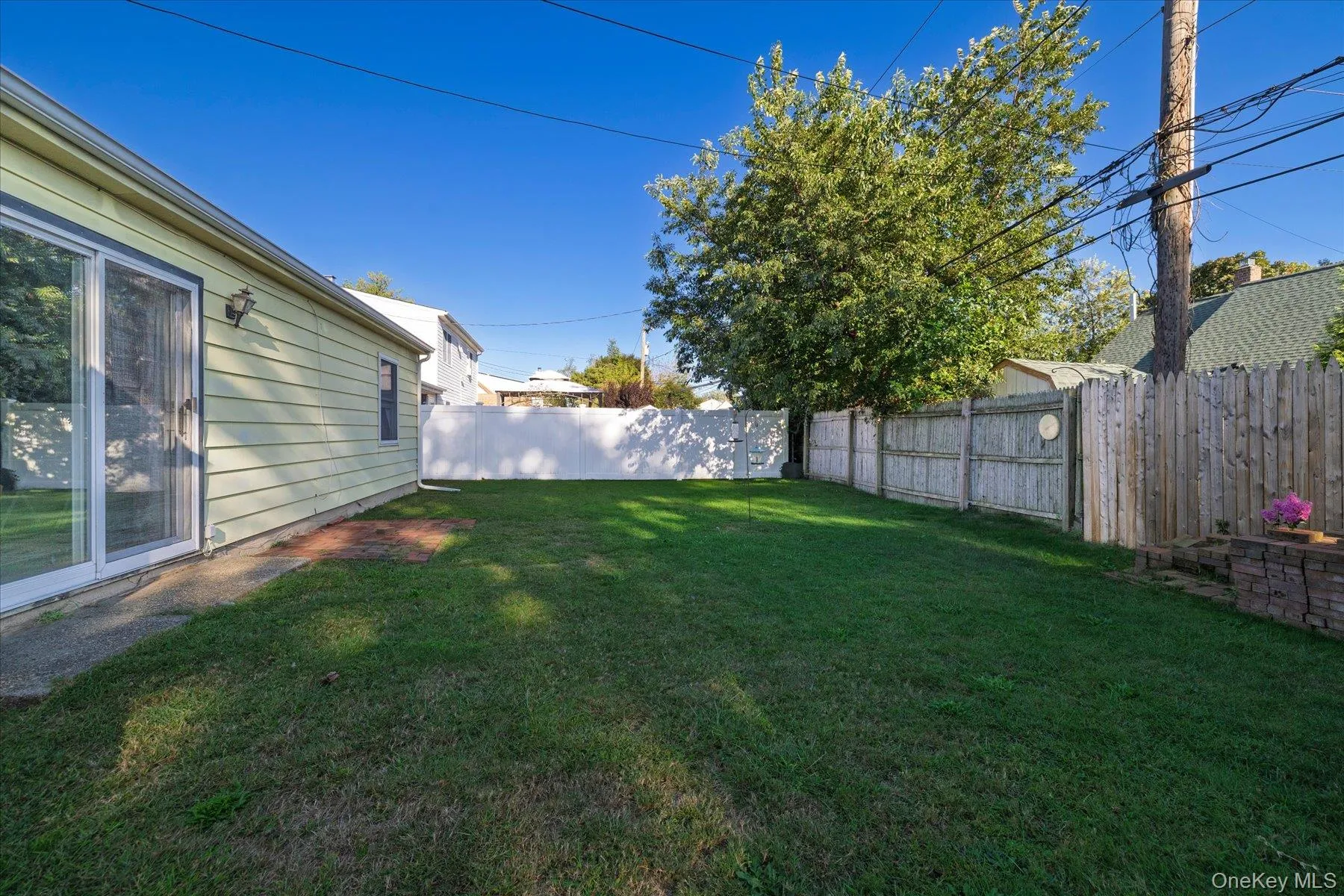Expansive backyard featuring a manicured lawn, privacy fencing, and a sliding glass door entry Expansive backyard featuring a manicured lawn, privacy fencing, and a sliding glass door entry