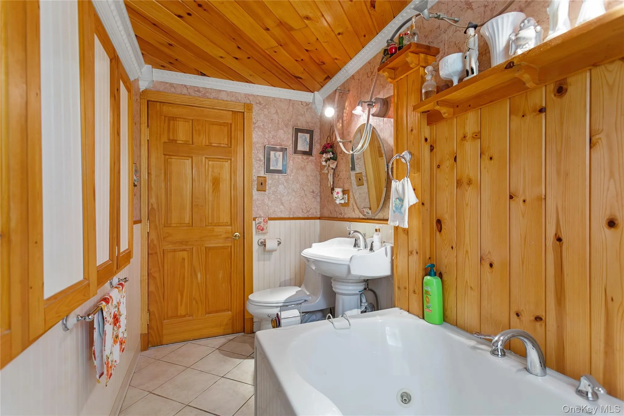 Bathroom featuring wallpapered walls, wainscoting, a whirlpool tub, tile patterned floors, and ornamental molding Bathroom featuring wallpapered walls, wainscoting, a whirlpool tub, tile patterned floors, and ornamental molding