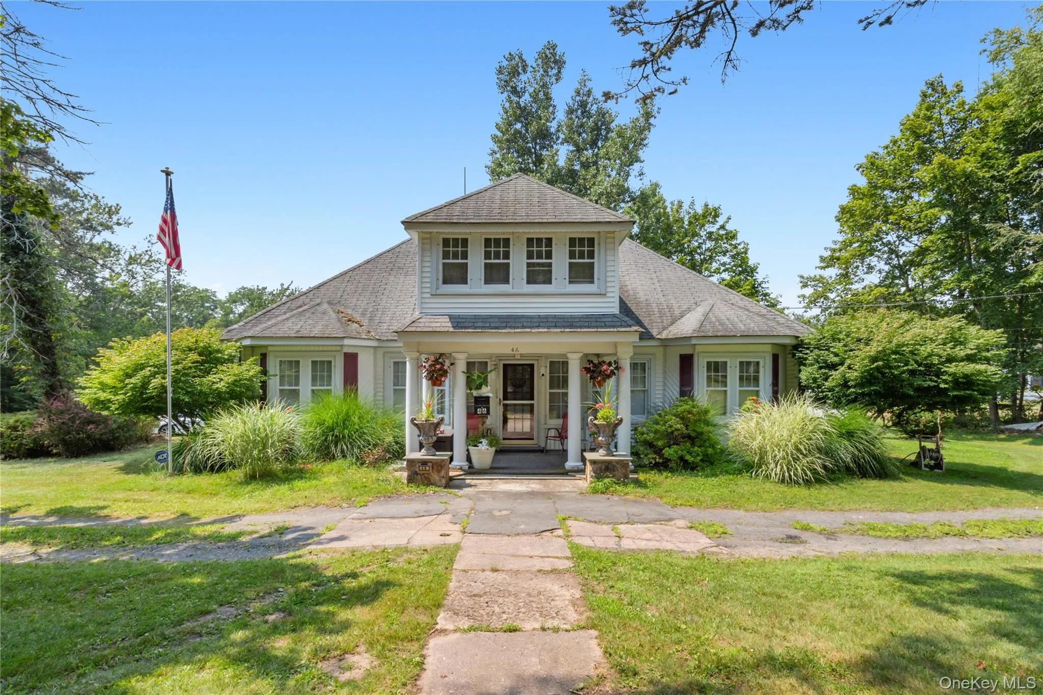 View of front of home with a porch, a shingled roof, and a front yard View of front of home with a porch, a shingled roof, and a front yard