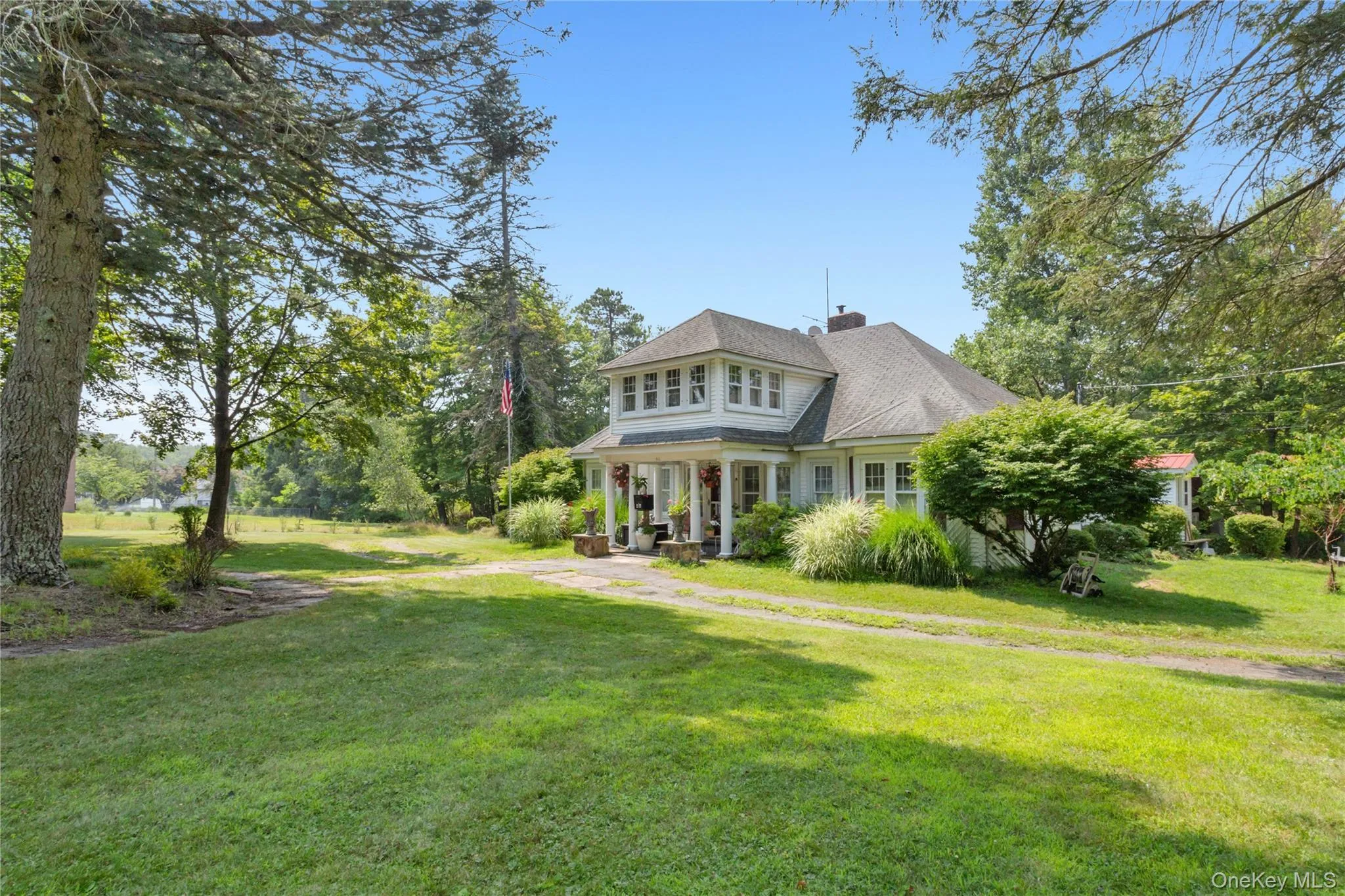 Shingle-style home with a chimney, a front lawn, roof with shingles, and a porch Shingle-style home with a chimney, a front lawn, roof with shingles, and a porch