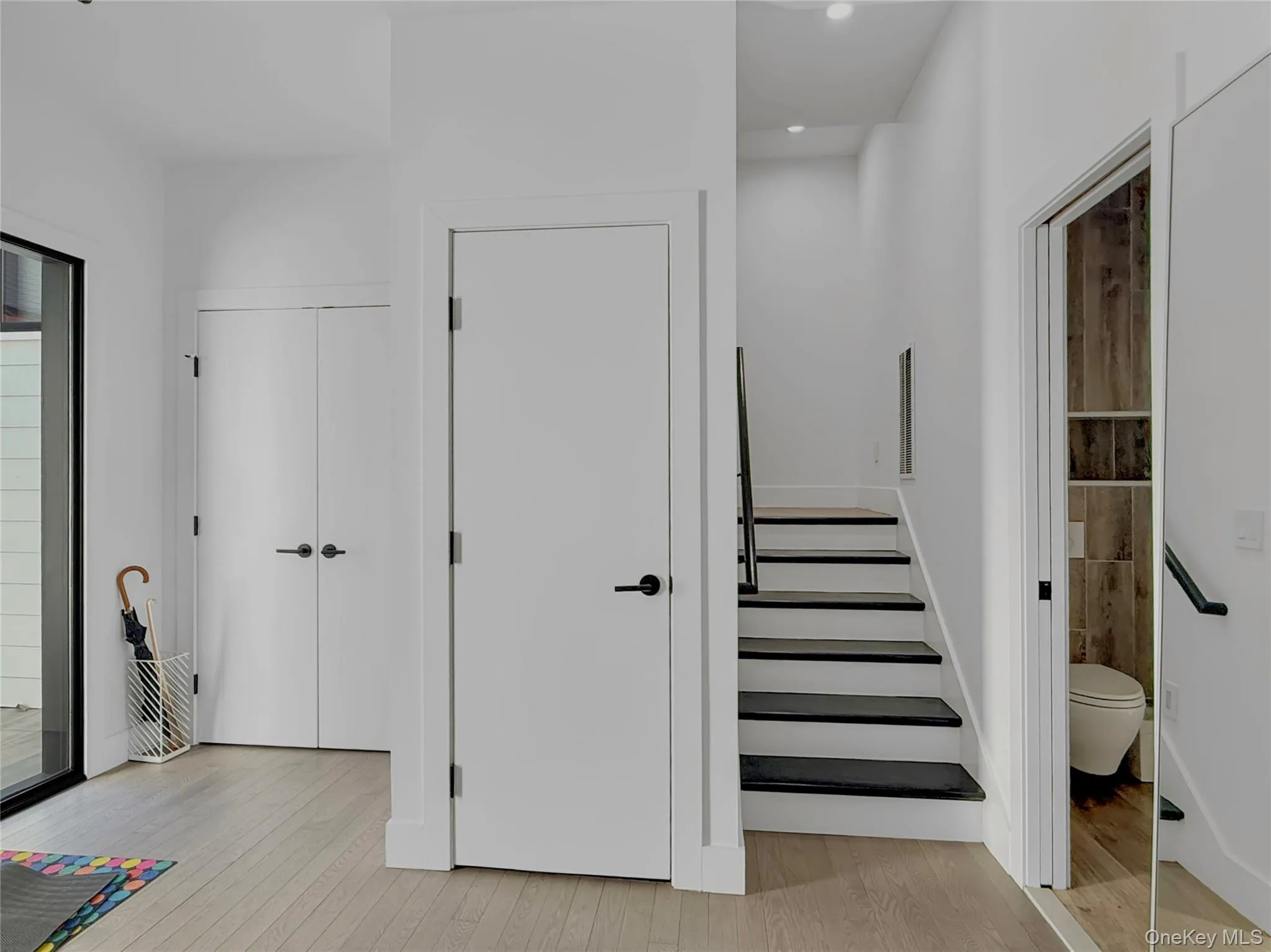 Stairs to second floor with coat closet and entrance to half bathroom Stairs to second floor with coat closet and entrance to half bathroom