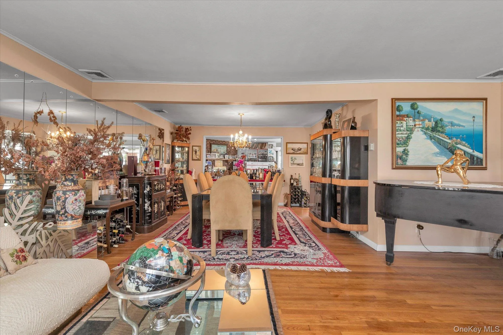 Hardwood flooring extends throughout this expansive interior space, featuring a dining area with a chandelier Hardwood flooring extends throughout this expansive interior space, featuring a dining area with a chandelier