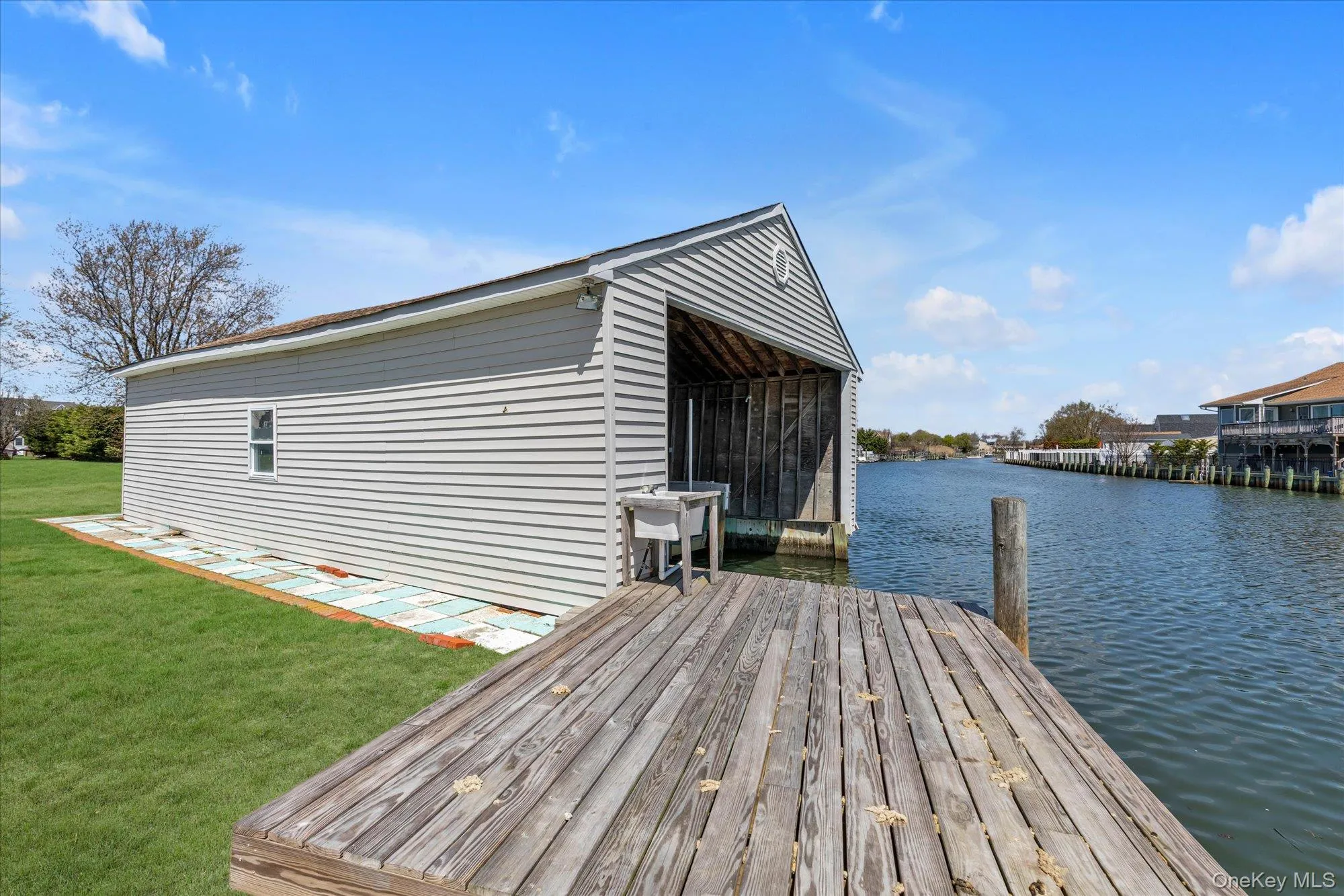 Boathouse with a dedicated slip, featuring gray horizontal siding and a gable roofline Boathouse with a dedicated slip, featuring gray horizontal siding and a gable roofline