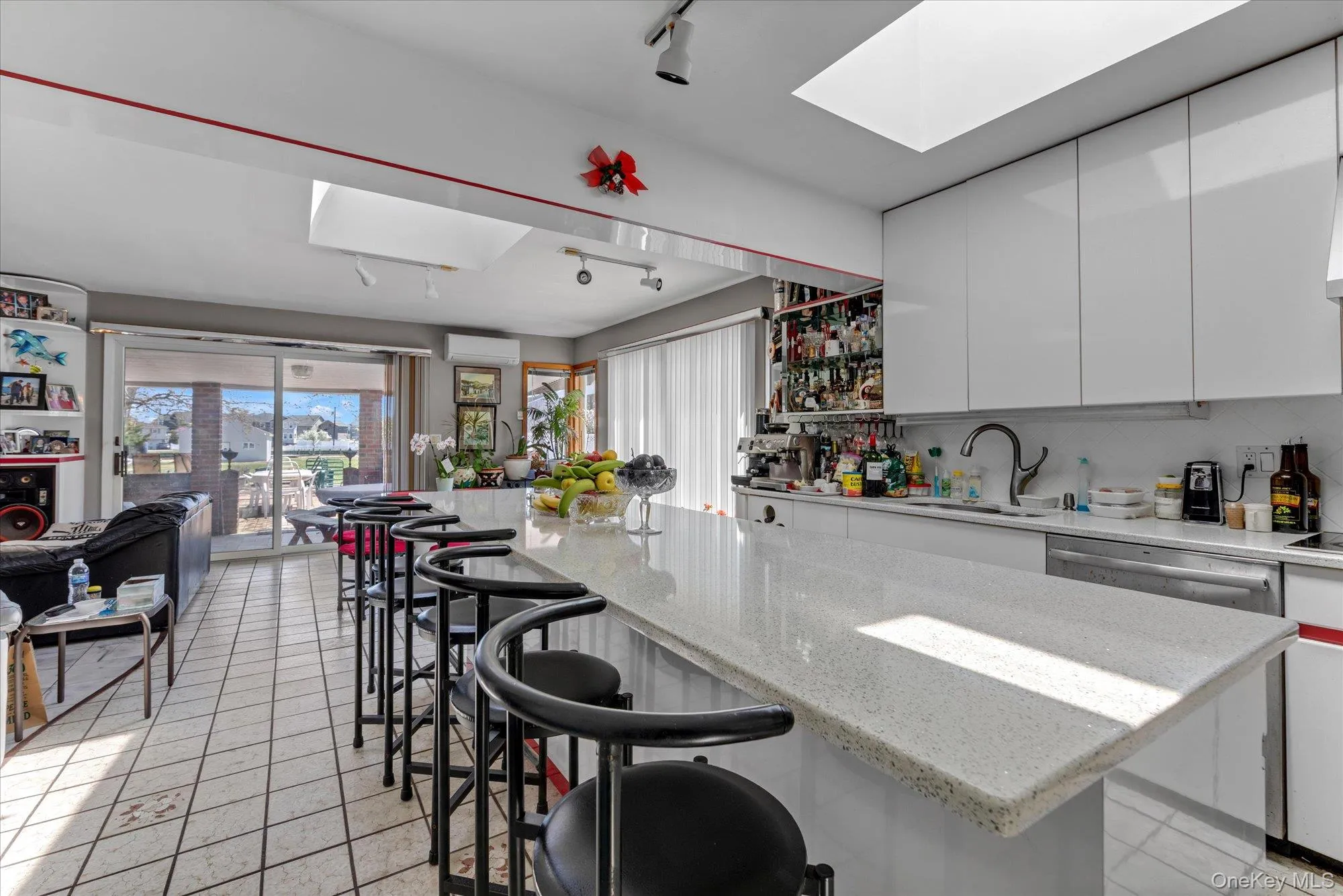 Kitchen featuring a spacious island with seating, white cabinetry, and a large skylight Kitchen featuring a spacious island with seating, white cabinetry, and a large skylight