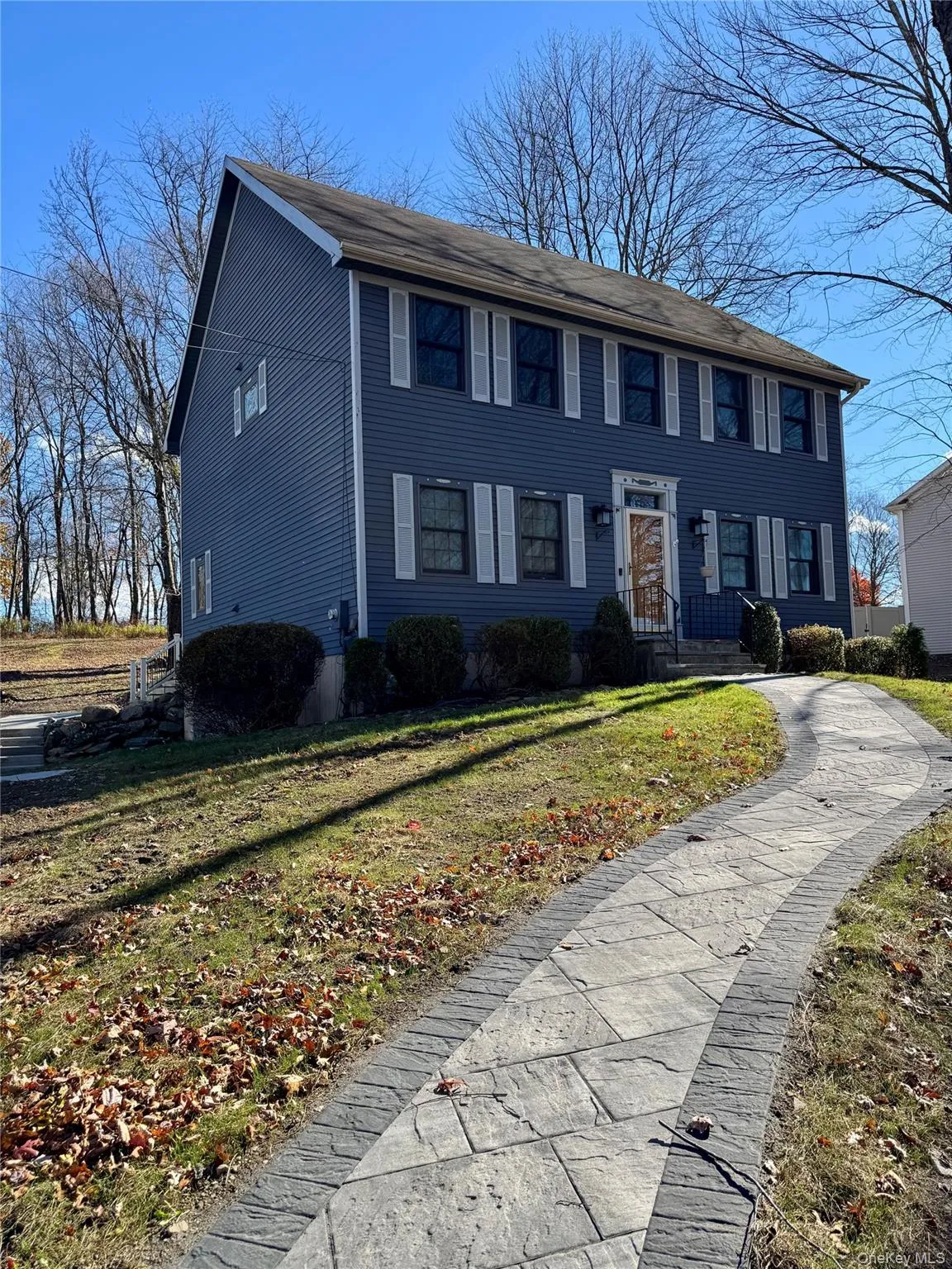 The property features a two-story exterior with blue siding and white window shutters, complemented by a winding stone-patterned walkway leading to the entrance The property features a two-story exterior with blue siding and white window shutters, complemented by a winding stone-patterned walkway leading to the entrance