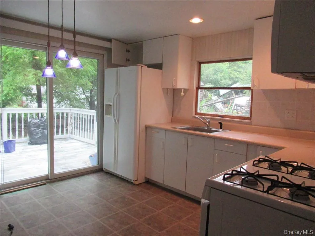 Kitchen with tile patterned flooring, white cabinetry, pendant lighting, stove, and sink Kitchen with tile patterned flooring, white cabinetry, pendant lighting, stove, and sink