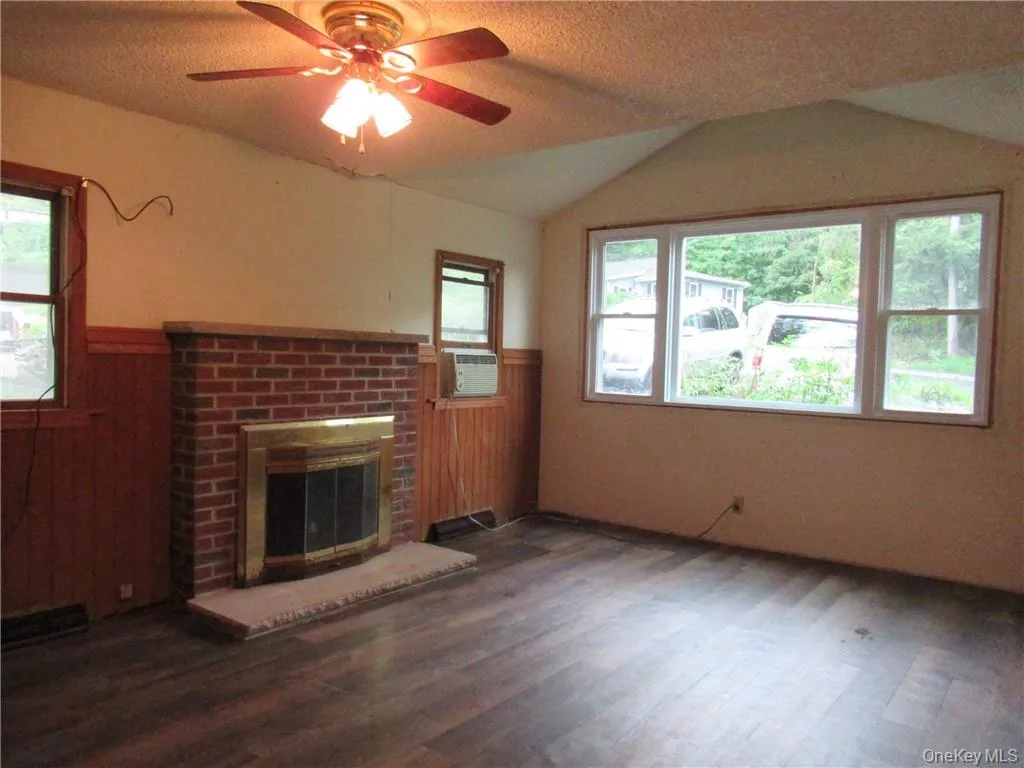 Unfurnished living room featuring dark hardwood / wood-style flooring, a fireplace, ceiling fan, and lofted ceiling Unfurnished living room featuring dark hardwood / wood-style flooring, a fireplace, ceiling fan, and lofted ceiling