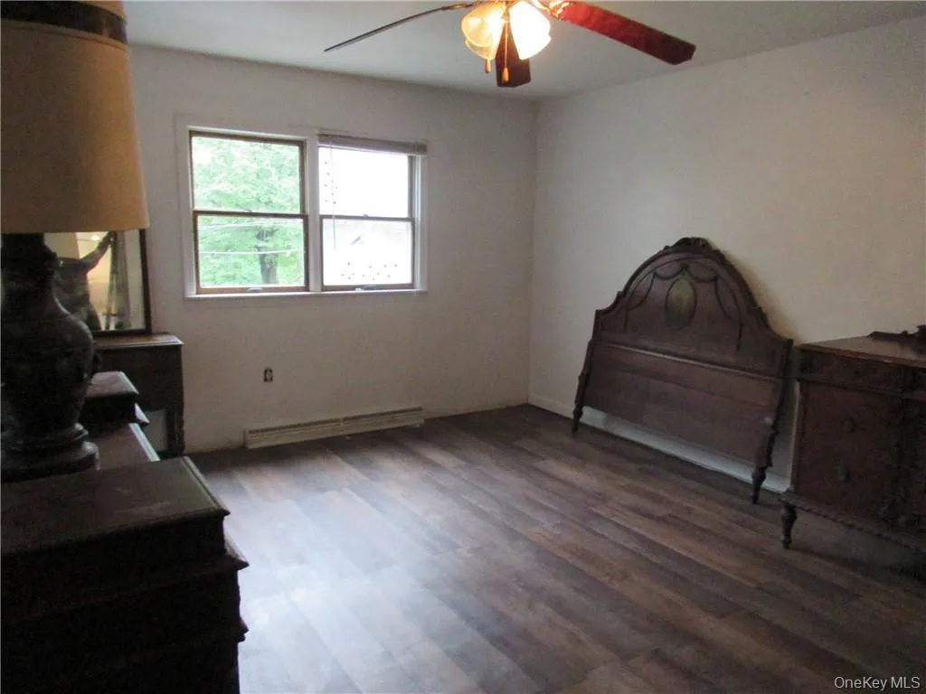 Bedroom with baseboard heating, hardwood / wood-style floors, and ceiling fan Bedroom with baseboard heating, hardwood / wood-style floors, and ceiling fan