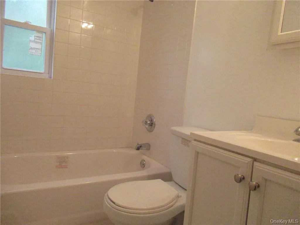 Full bathroom with vanity, tiled shower / bath combo, and toilet Full bathroom with vanity, tiled shower / bath combo, and toilet