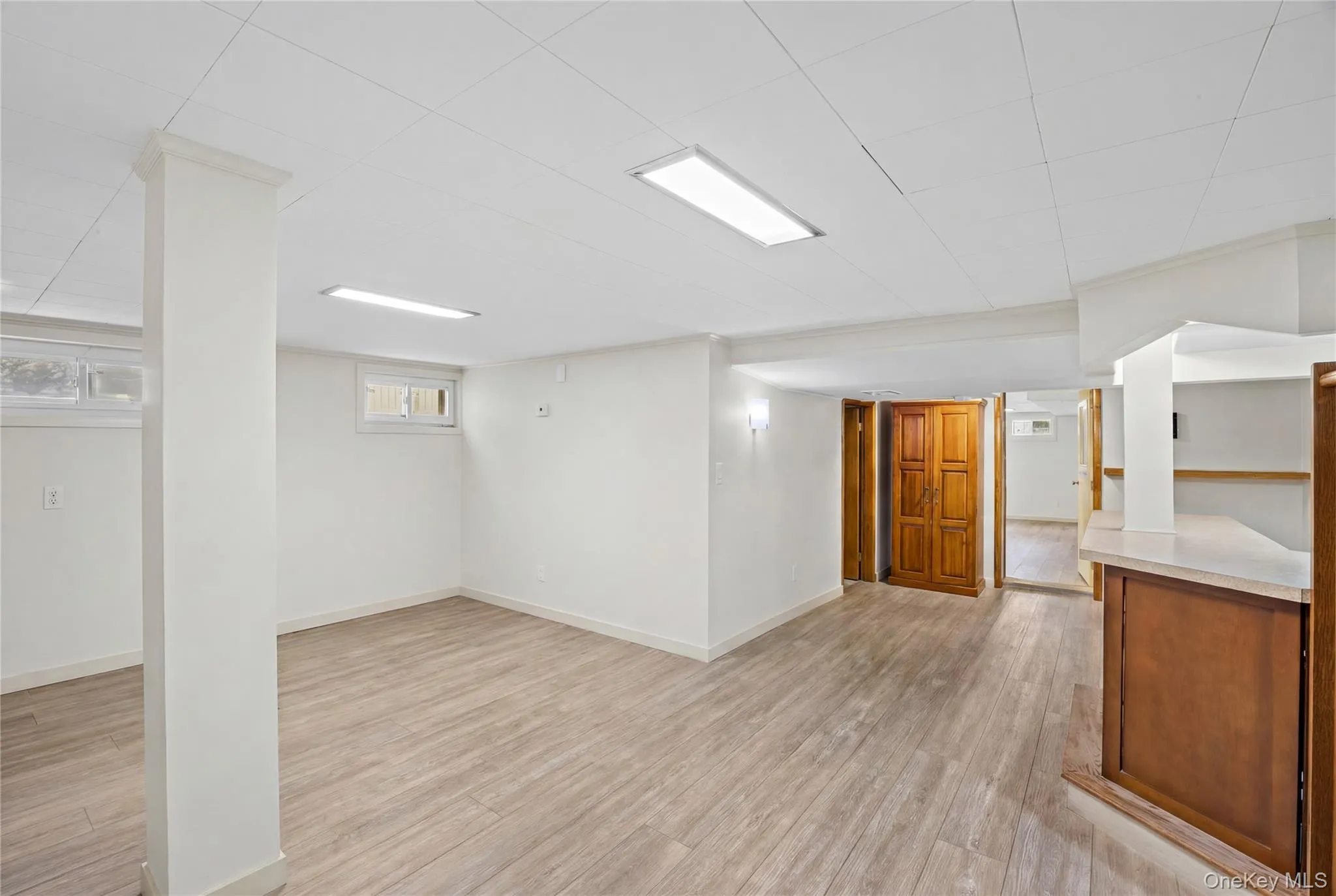 This expansive room features light-toned flooring, white walls, and a white ceiling with recessed lighting This expansive room features light-toned flooring, white walls, and a white ceiling with recessed lighting