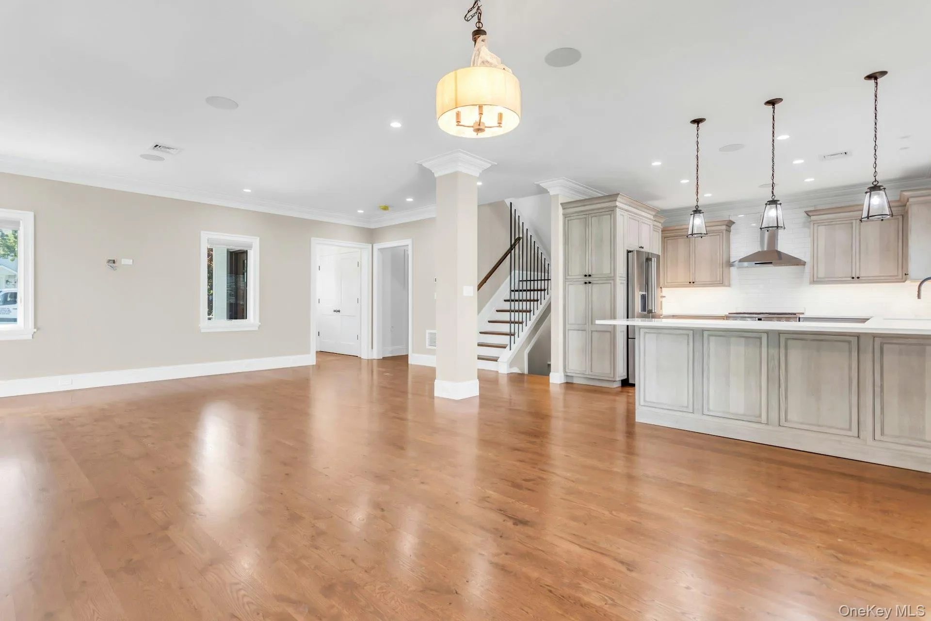 Open concept living area with hardwood floors, a kitchen island, and a staircase with dark wood treads and a metal railing Open concept living area with hardwood floors, a kitchen island, and a staircase with dark wood treads and a metal railing