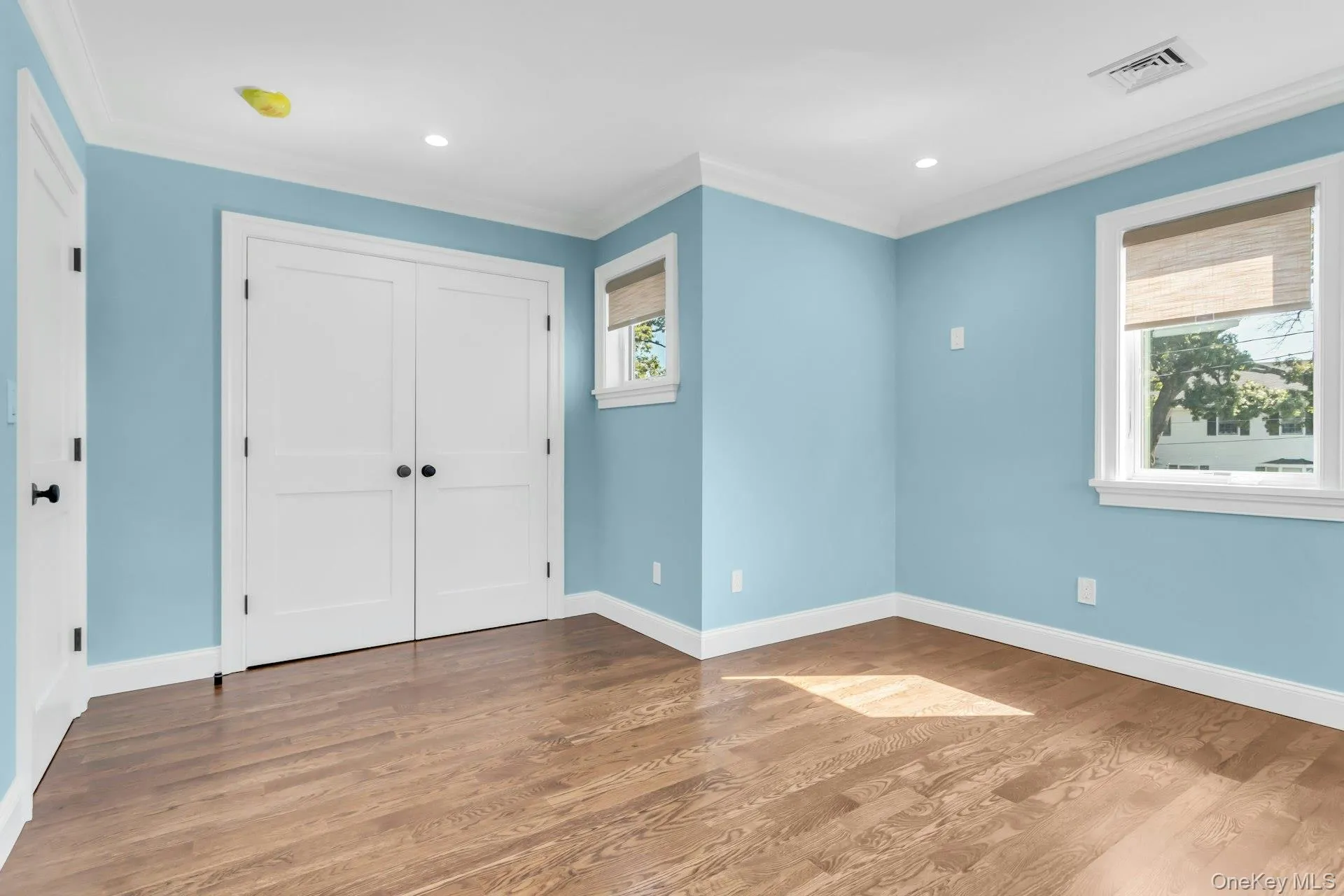 This room features hardwood floors, light blue walls, and white trim This room features hardwood floors, light blue walls, and white trim
